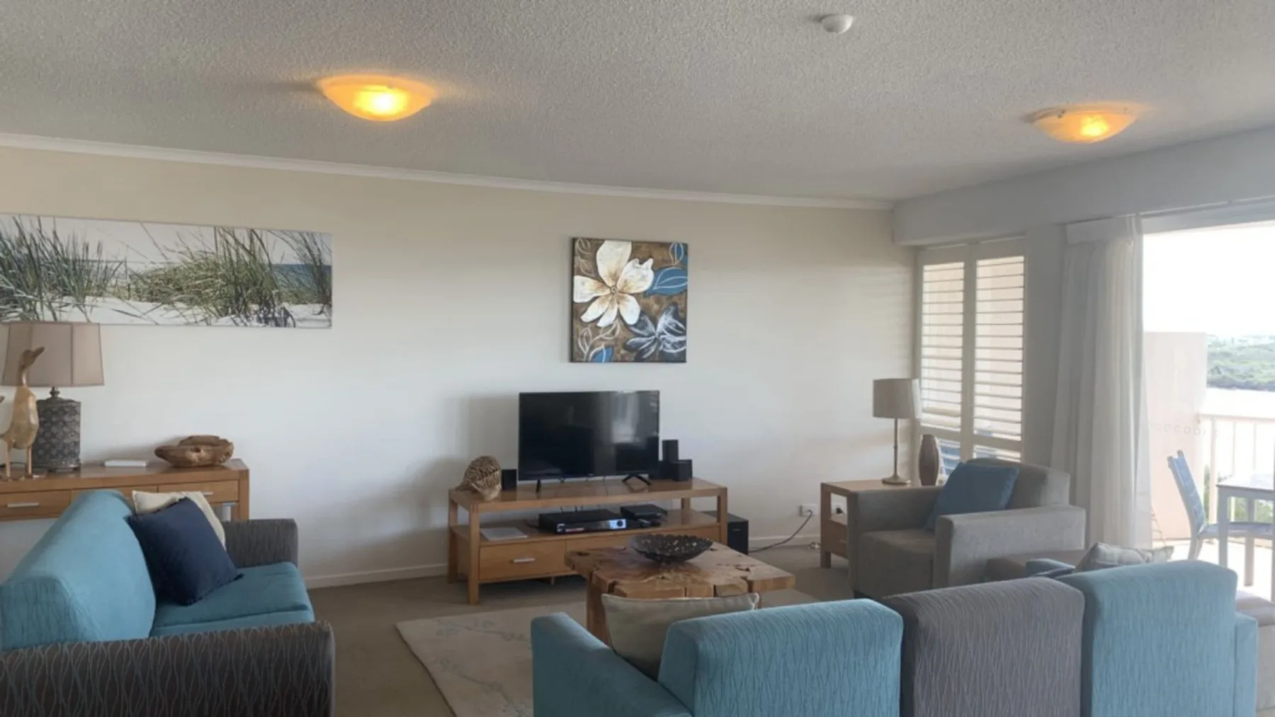 Una sala de estar con asientos azules, un televisor y una mesa de centro.