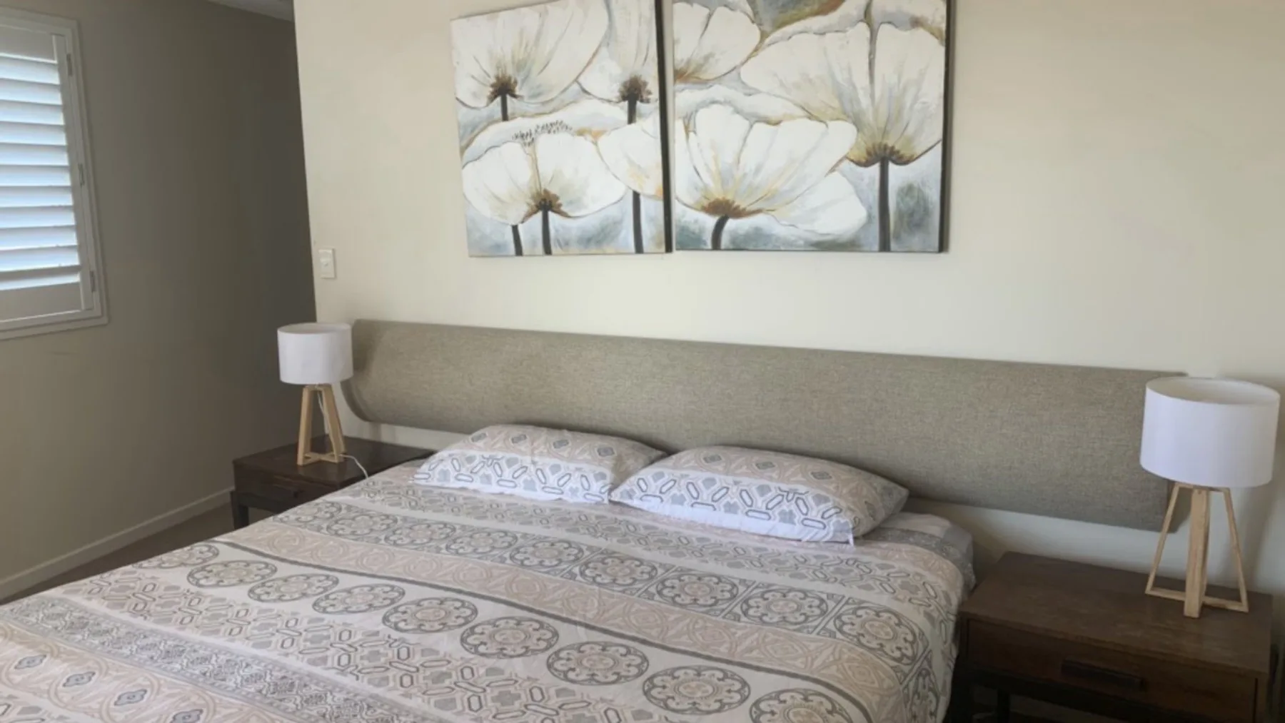 Un dormitorio con una colcha estampada y un cuadro floral sobre la cama.
