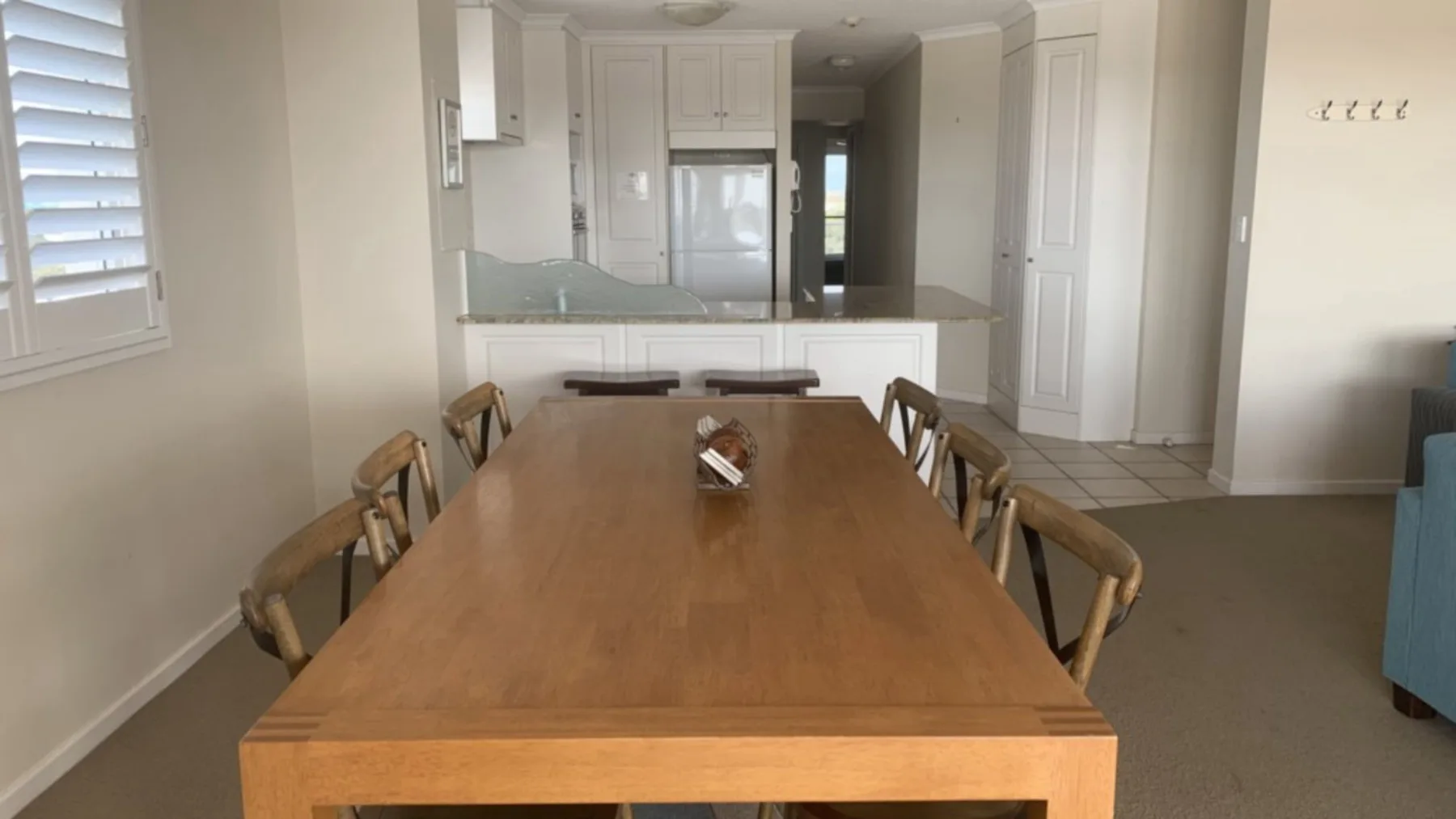 Comedor con una mesa larga de madera y sillas, junto a una cocina abierta.