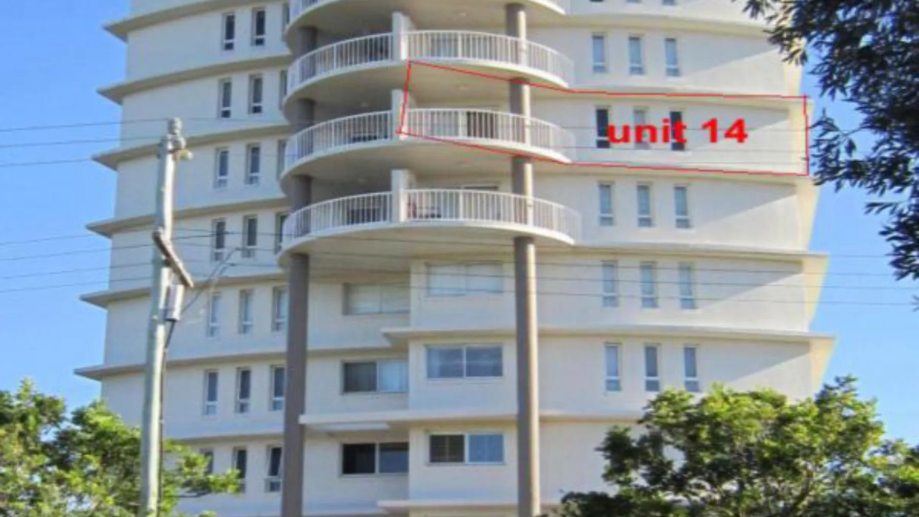 Edificio de apartamentos de varios pisos con balcones curvos y un letrero de la unidad 14.
