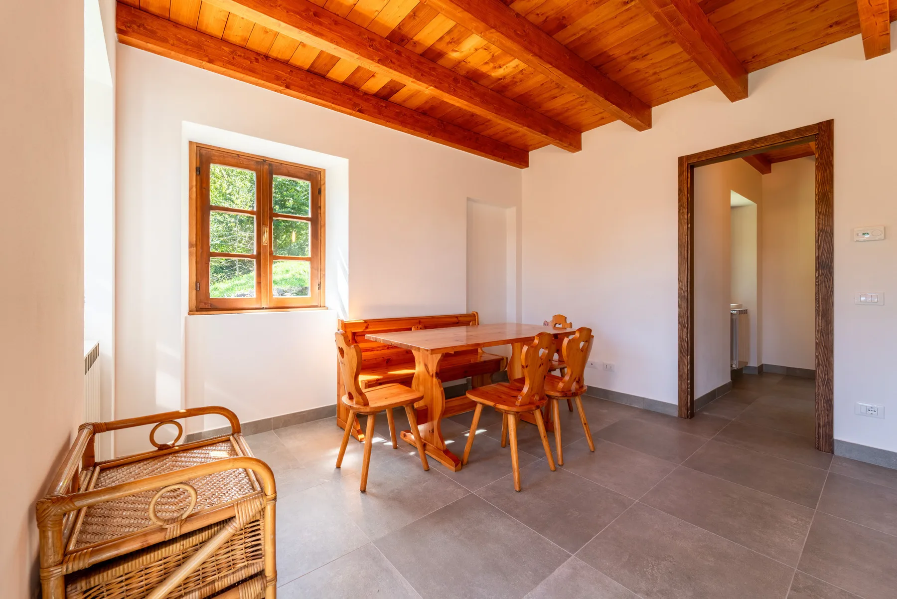 Un comedor con una mesa y sillas de madera bajo vigas expuestas.