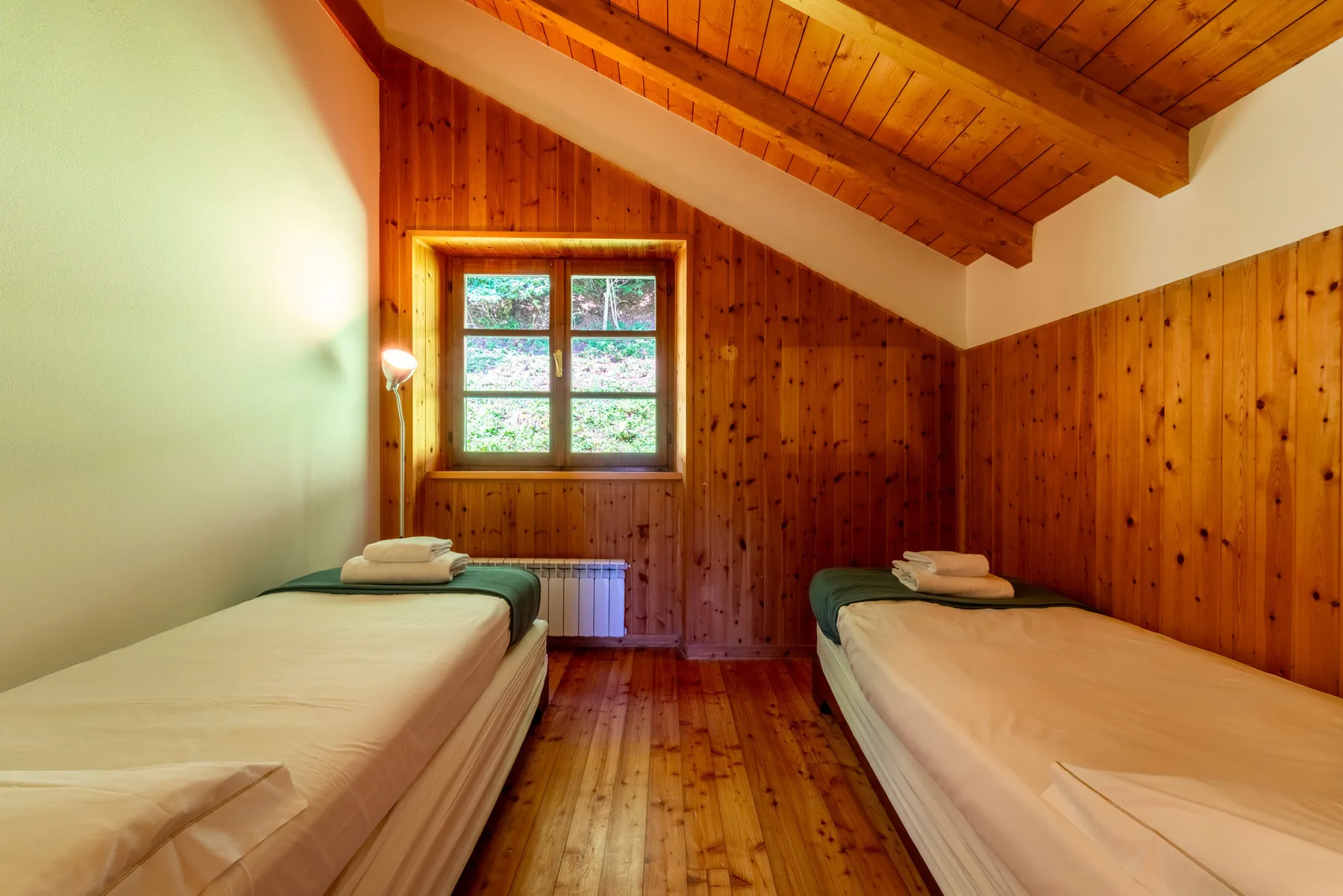 Un dormitorio con dos camas individuales bajo un techo de madera inclinado.