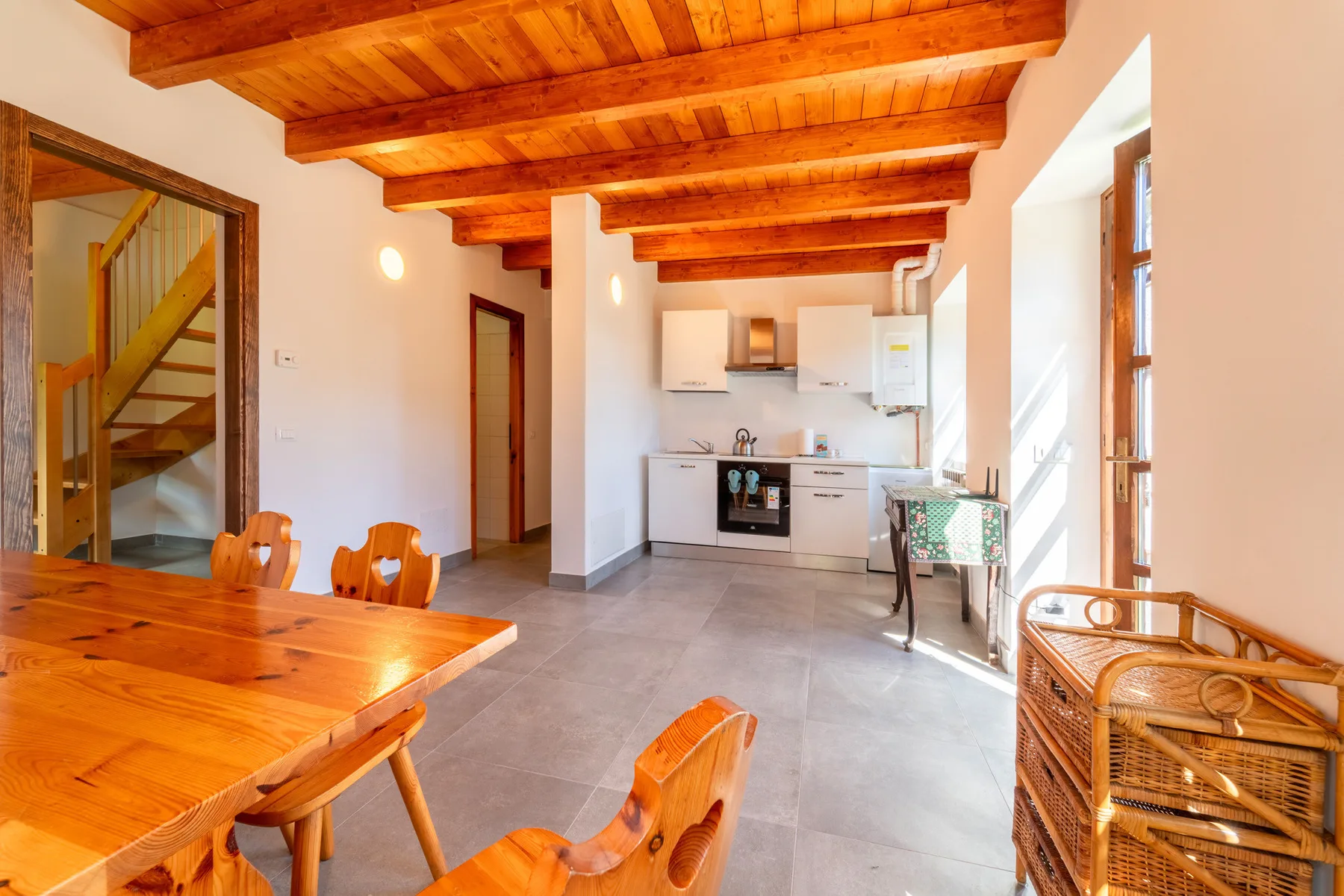 Una luminosa cocina-comedor con vigas de madera y una amplia mesa de comedor.