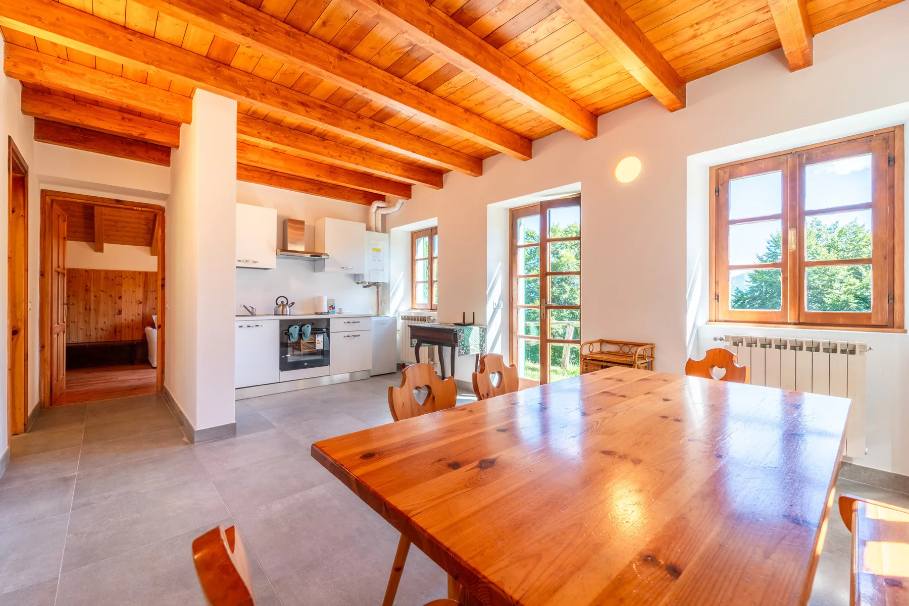Comedor con una mesa grande de madera junto a una cocina abierta.