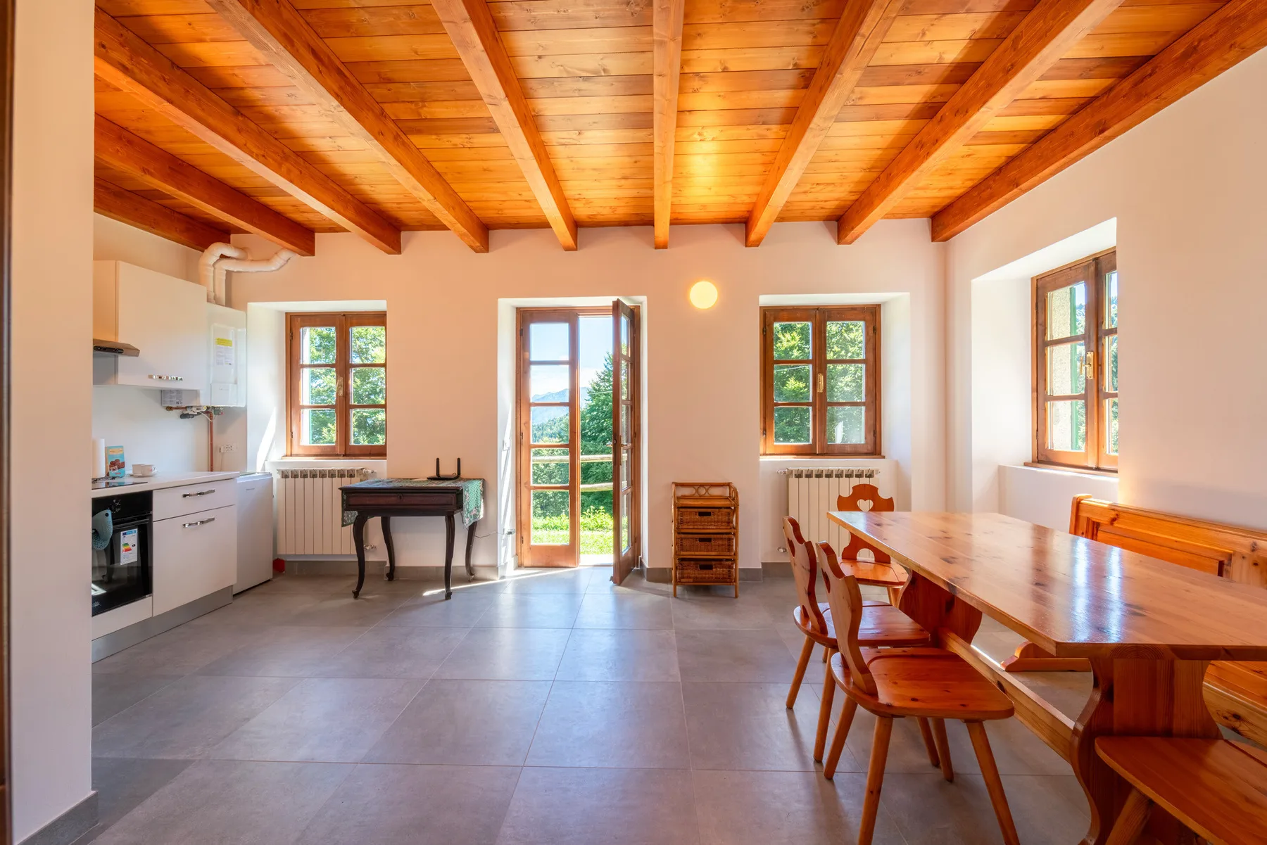 Una cocina y comedor luminosos con asientos de madera y ventanas grandes.