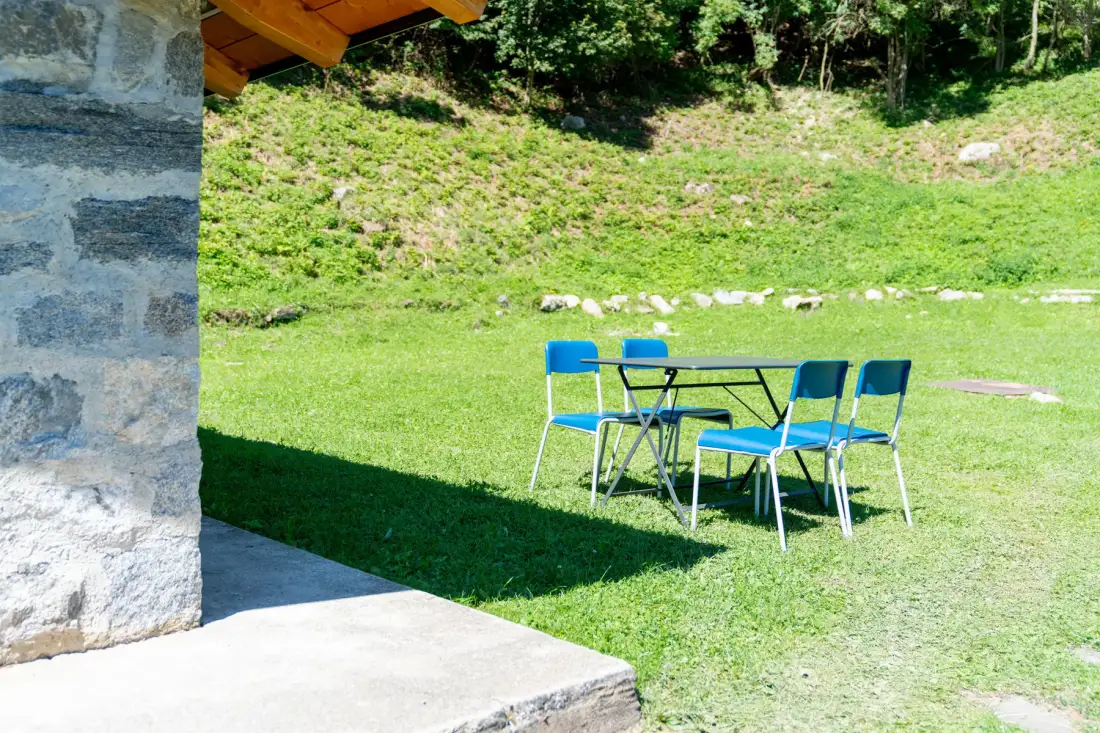 Una mesa y asientos al aire libre están junto a una ladera cubierta de hierba.