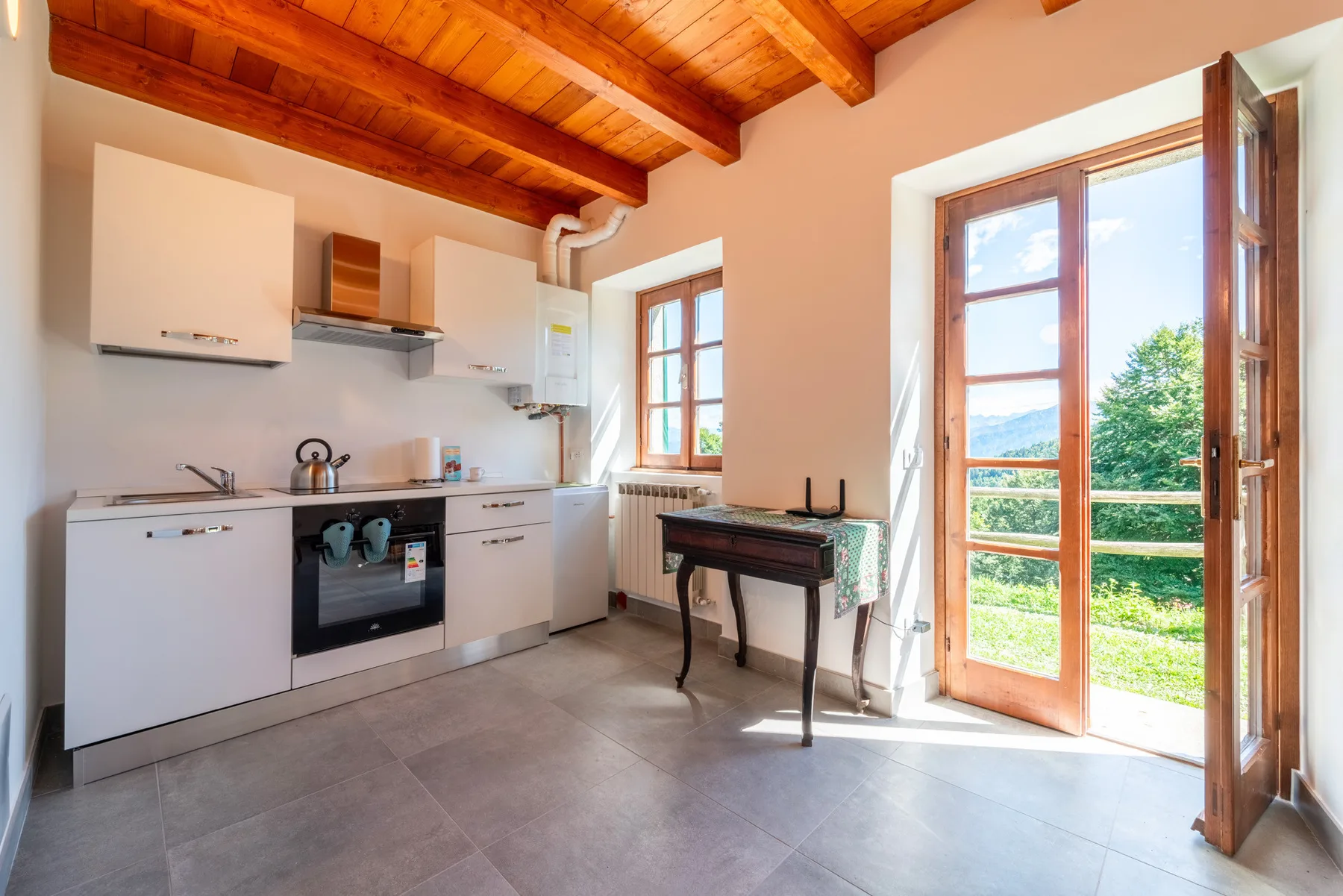 Una cocina con una mesa pequeña junto a puertas abiertas al exterior.