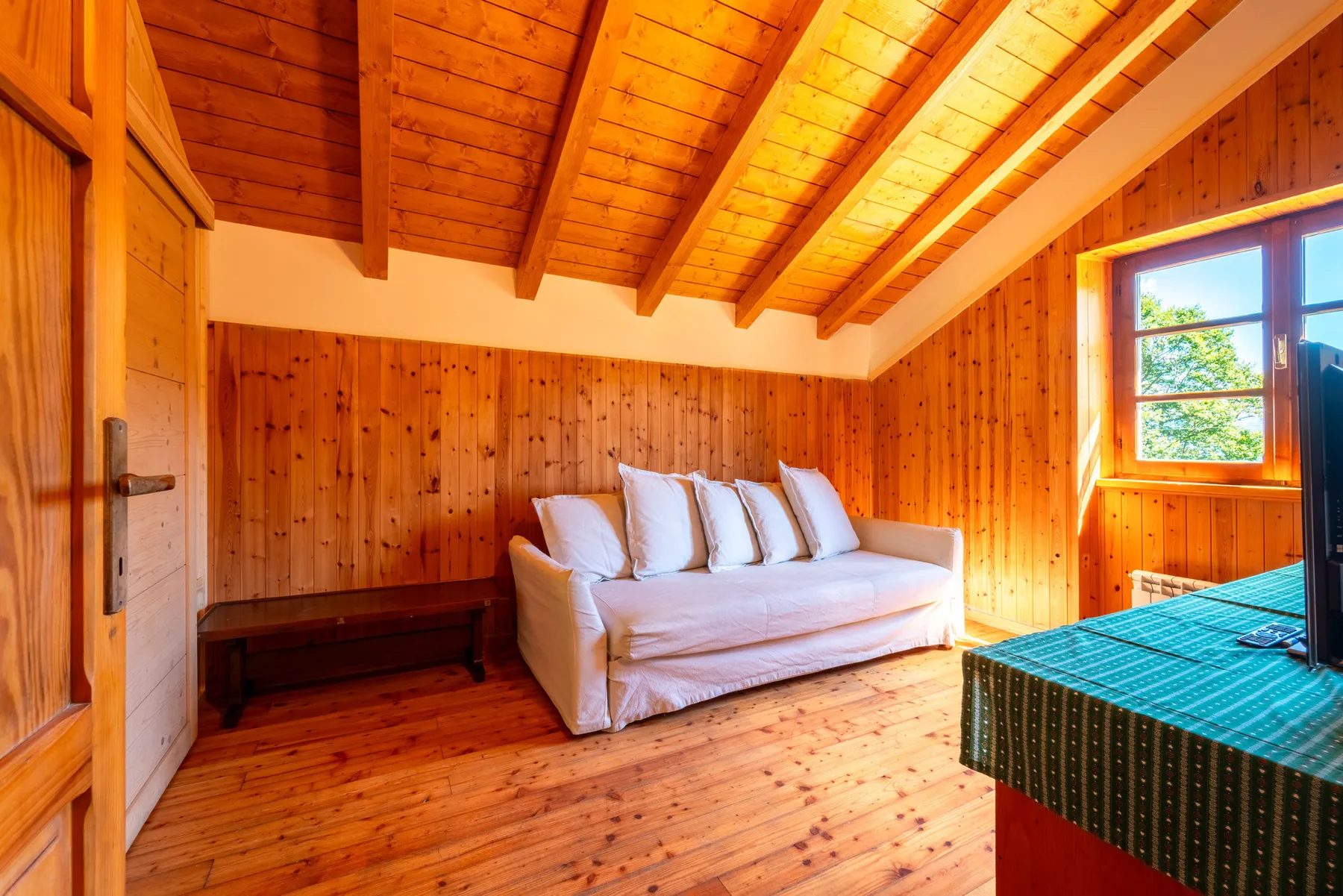 Una habitación revestida de madera con un sofá blanco y una mesa junto a una ventana.