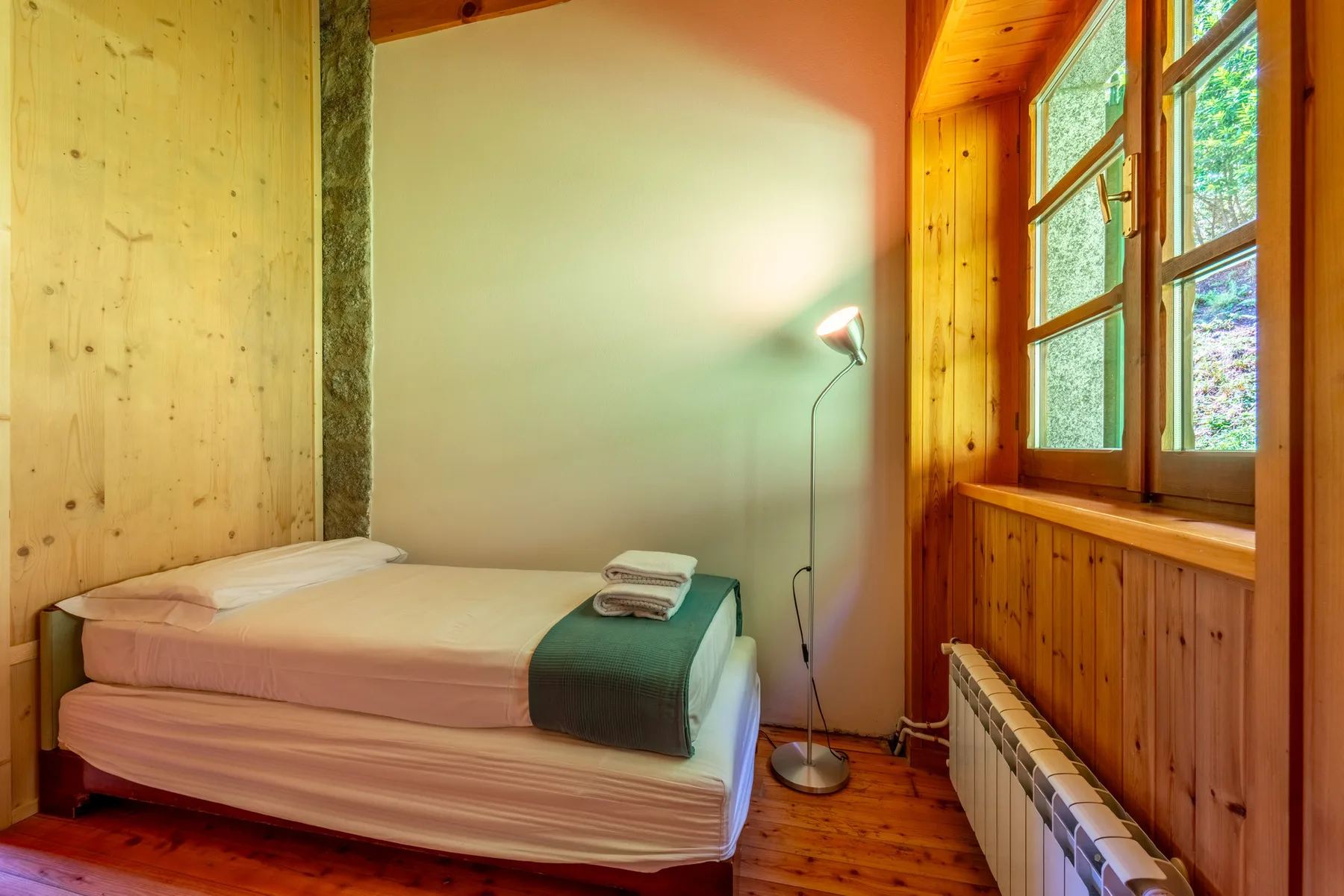 Un dormitorio con una cama bien arreglada junto a una ventana grande.