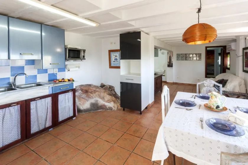 A kitchen and dining area with blue cabinets, a tiled floor, and a set table.