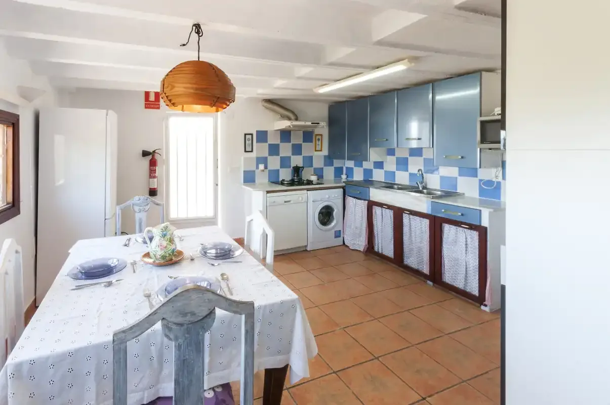 A kitchen and dining area with blue cabinets and a set table.
