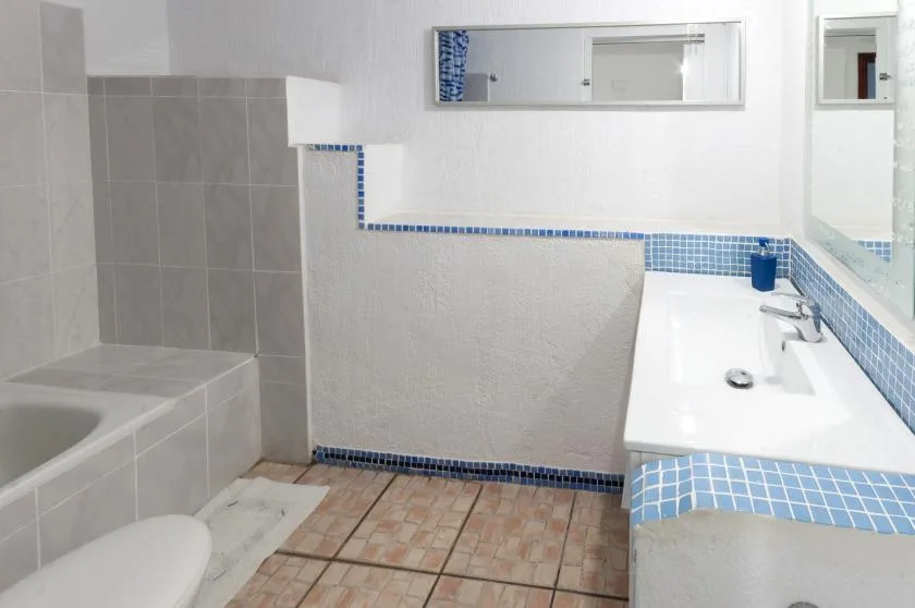 A tiled bathroom with a bathtub, a sink, and a wall mirror.