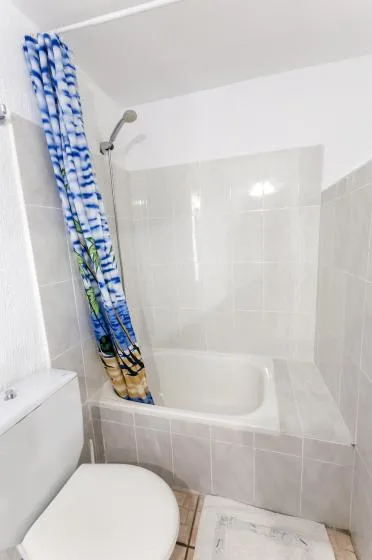 A tiled bathroom with a bathtub, showerhead, and patterned shower curtain.