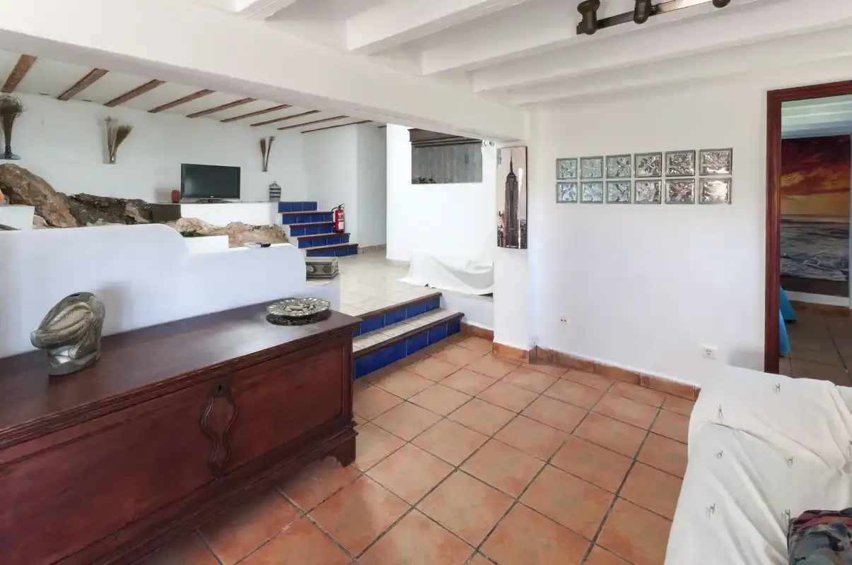 A tiled living area with seating, a dark wooden cabinet, and steps.