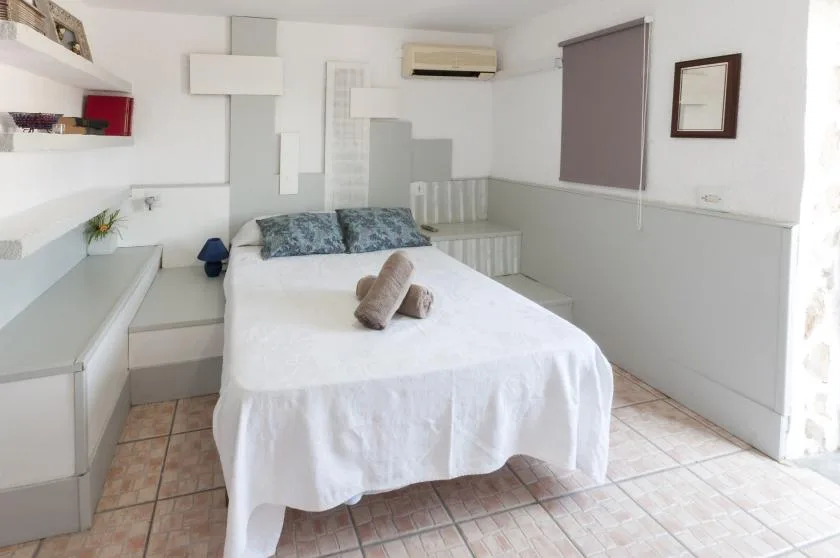 A bright bedroom with a neatly made bed and built-in shelving.