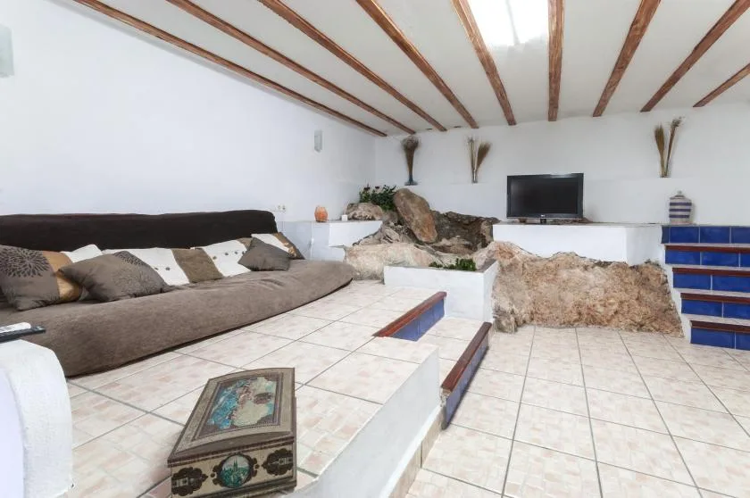 A tiled living room with low seating, decorative rocks, and a television.