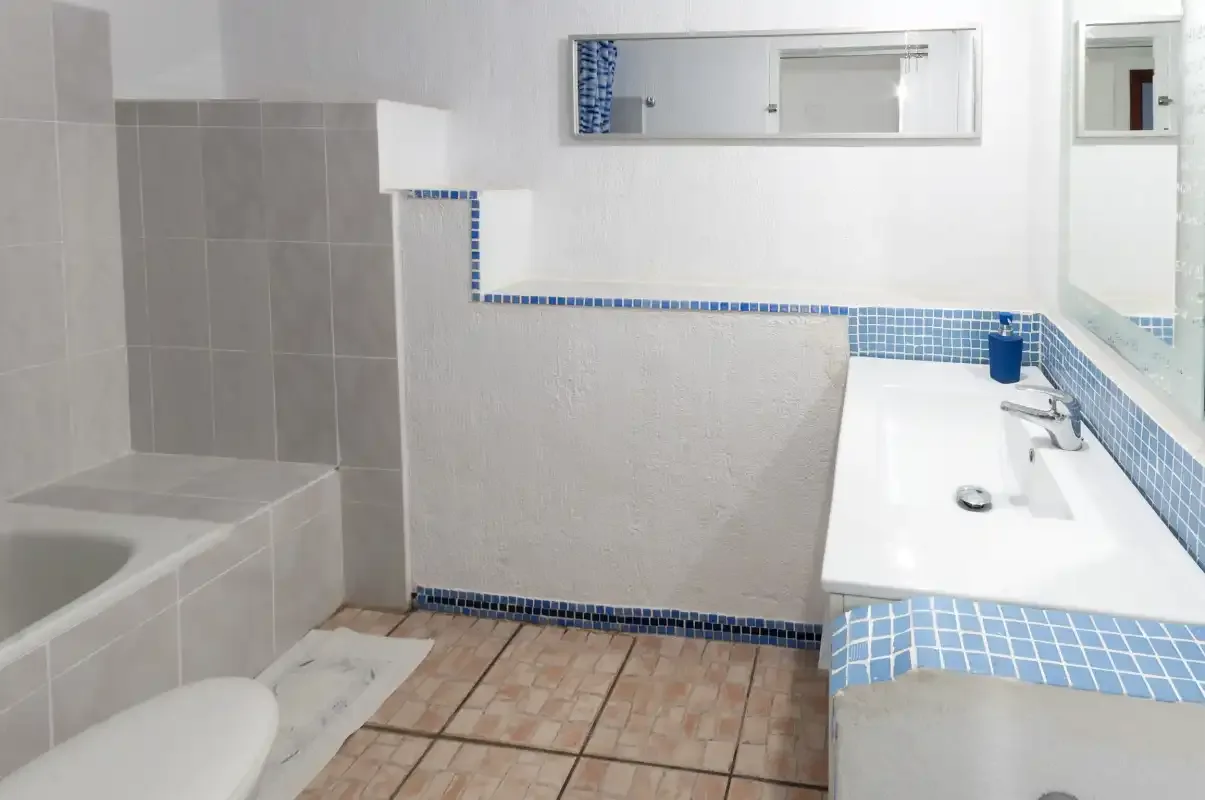 A tiled bathroom with a bathtub and a sink along the wall.