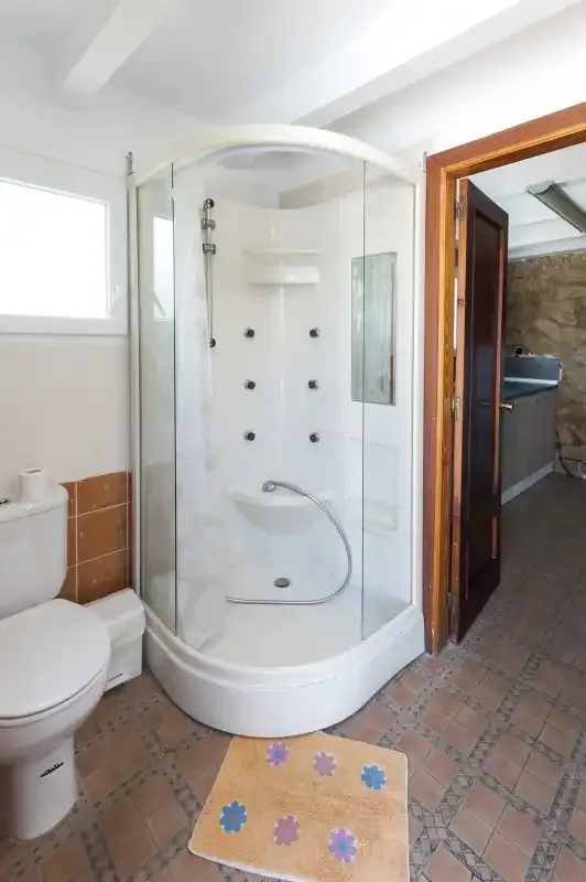 A bathroom with a curved glass shower and a toilet.