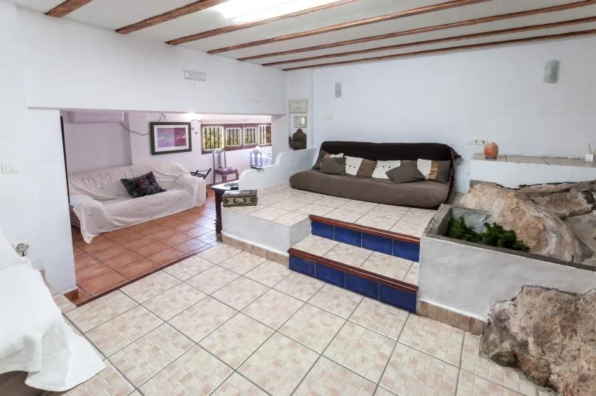 A tiled living room with seating, a raised platform, and an indoor planter.