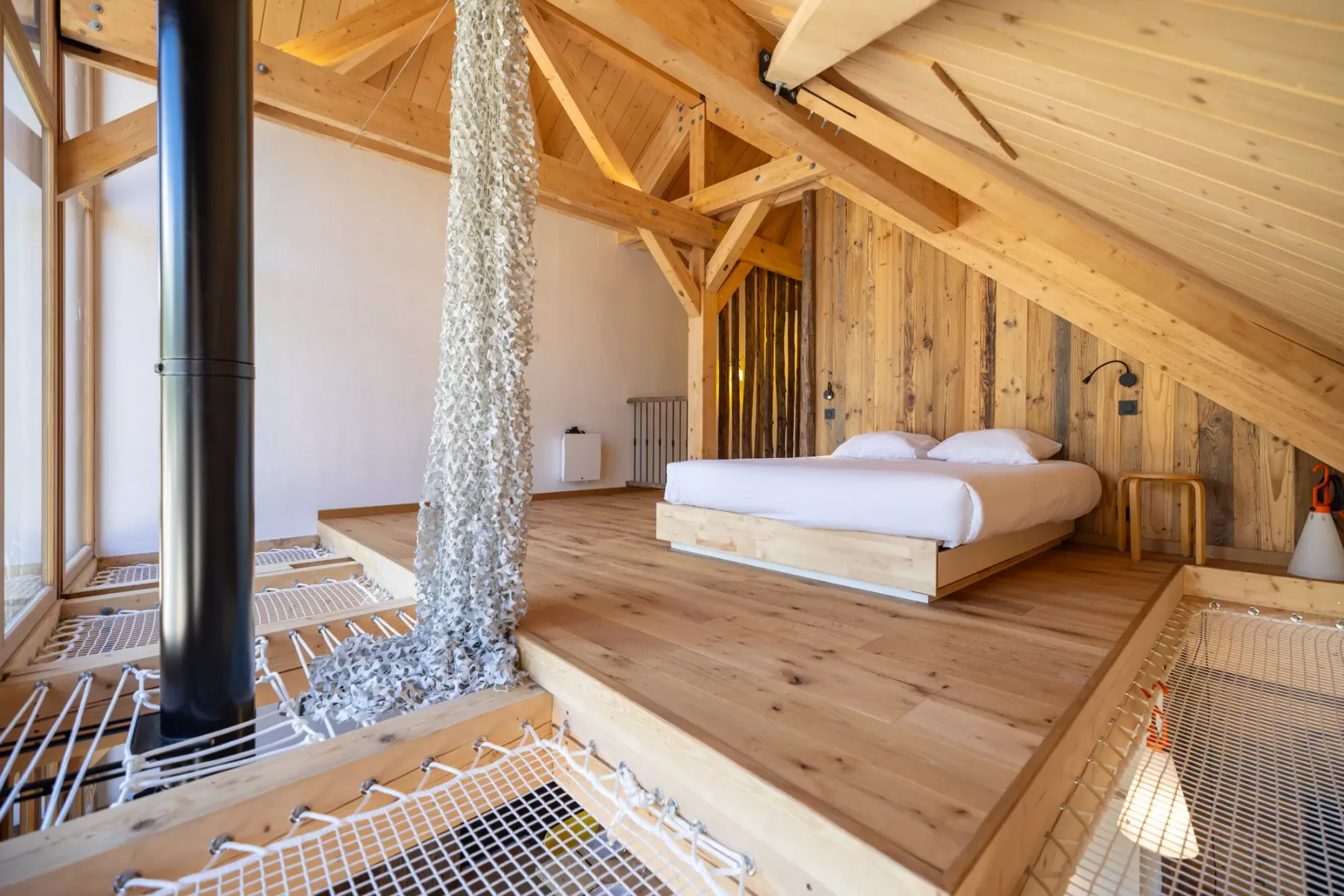 Un dormitorio en un altillo de madera con una cama bajo vigas expuestas.