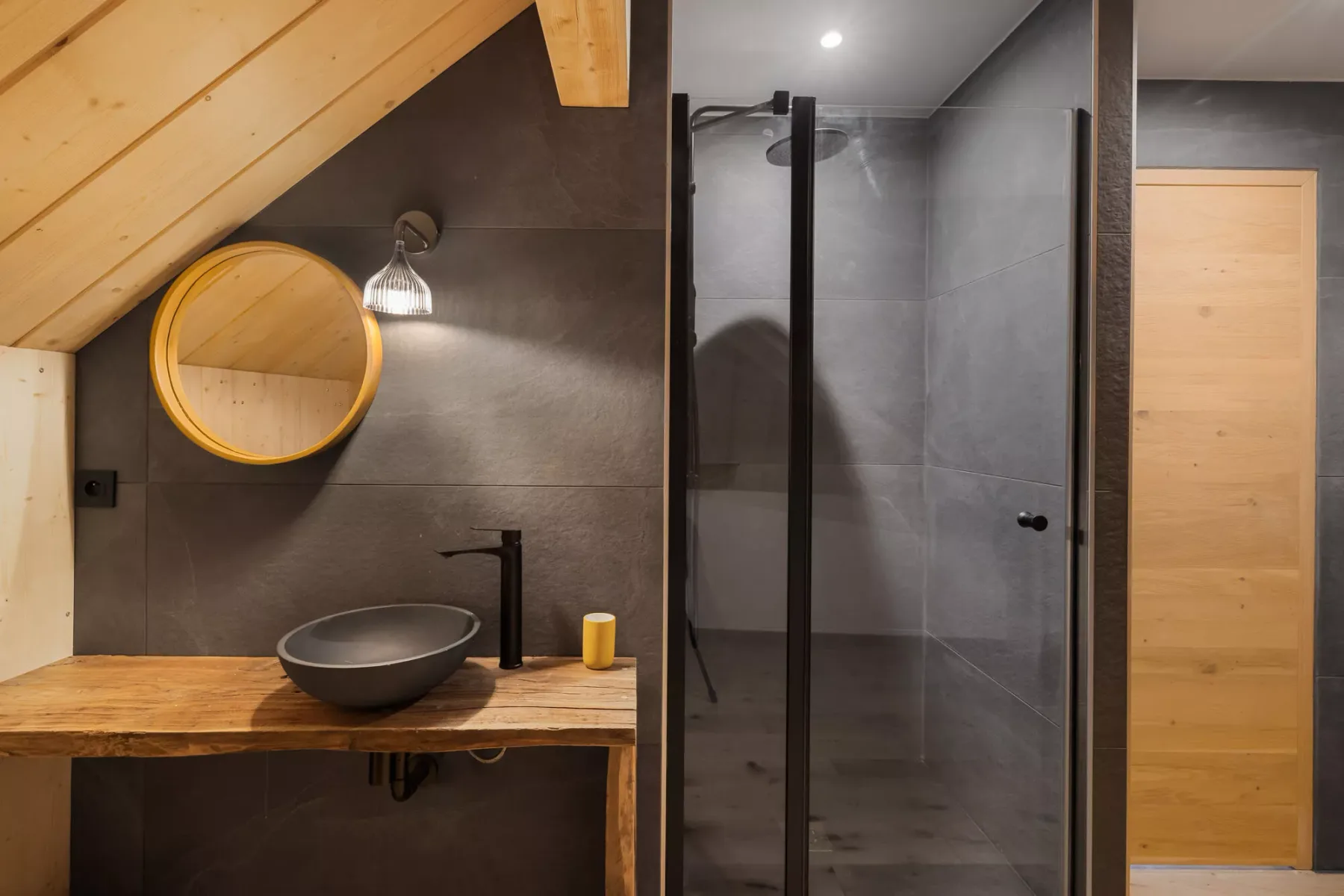 Un lavabo de baño con espejo redondo junto a una ducha de vidrio.