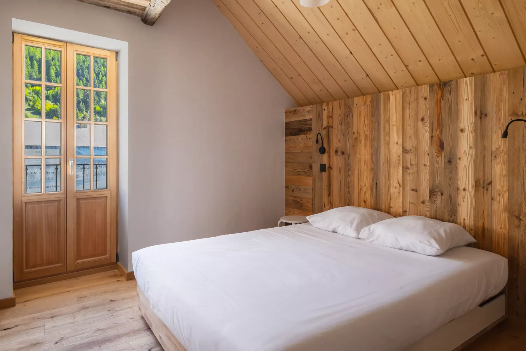 Un dormitorio con una cama bajo un techo inclinado de madera.