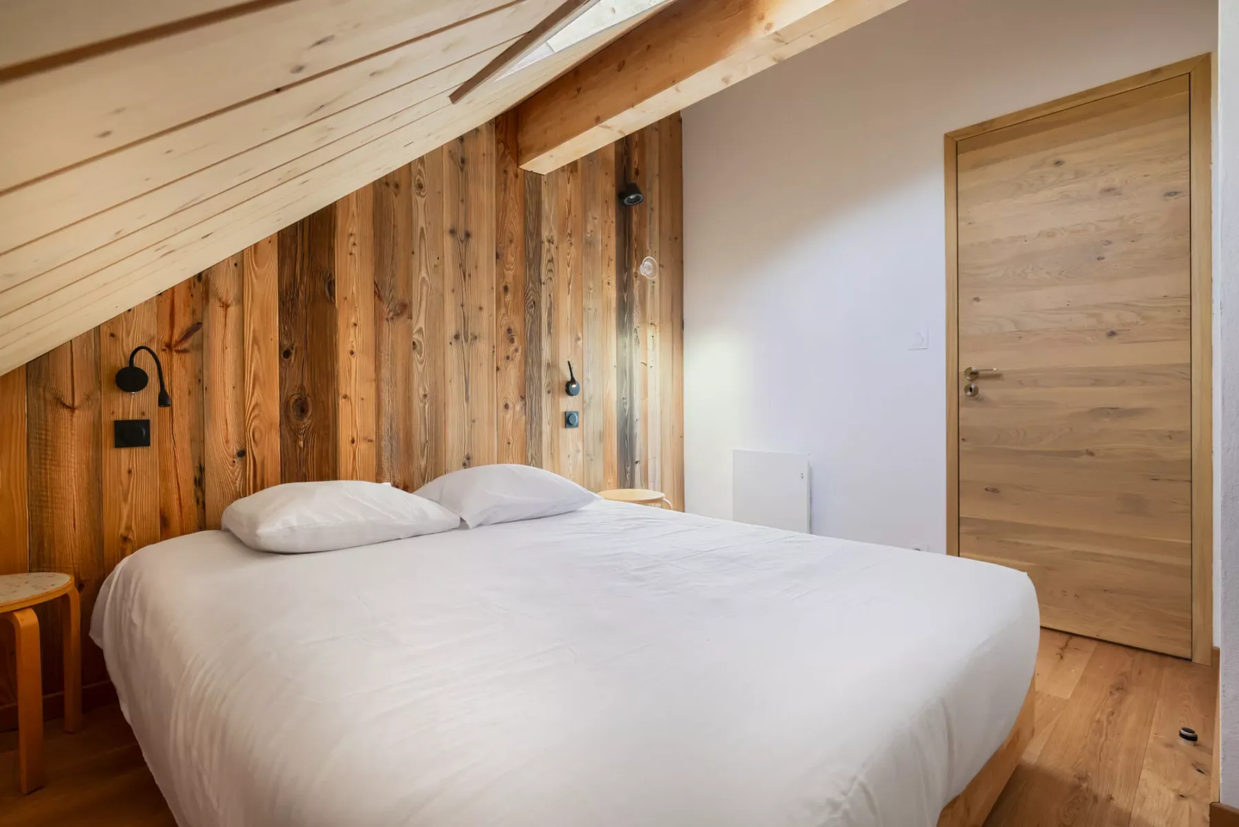 Un dormitorio con una cama grande bajo un techo inclinado de madera.