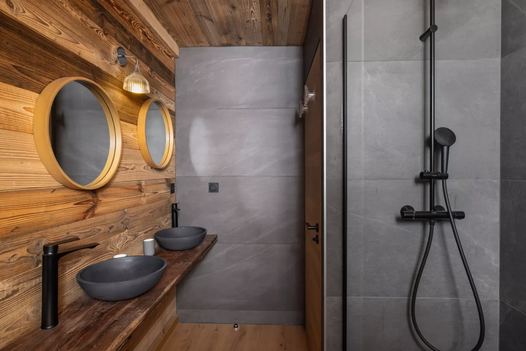 Un baño con un tocador revestido de madera y una ducha de vidrio.