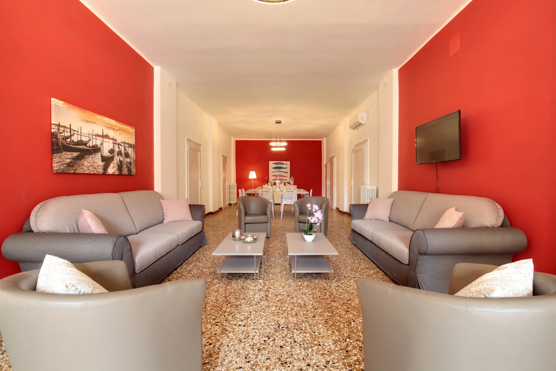 A lounge with seating arranged along red walls around a central coffee table.