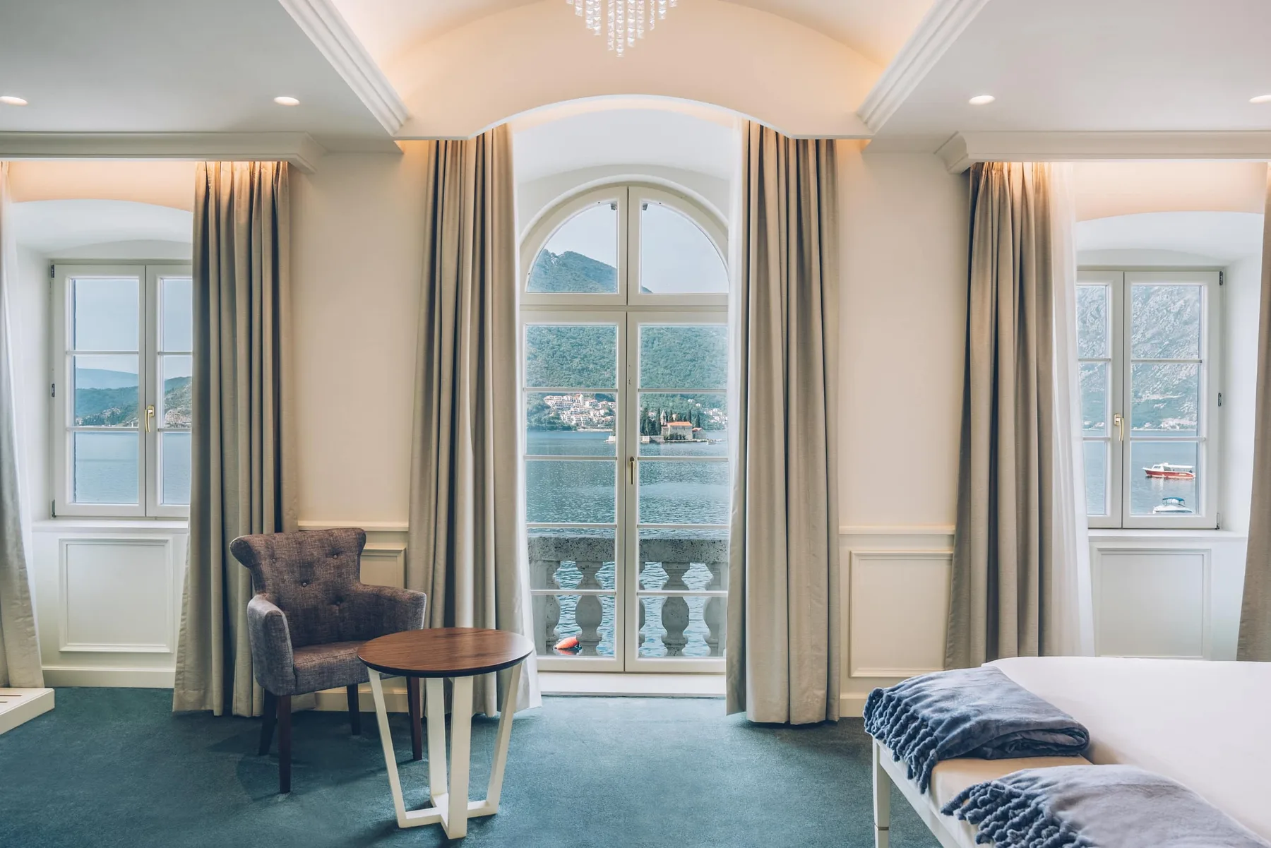 Hotel room with tall windows overlooking the sea and mountains