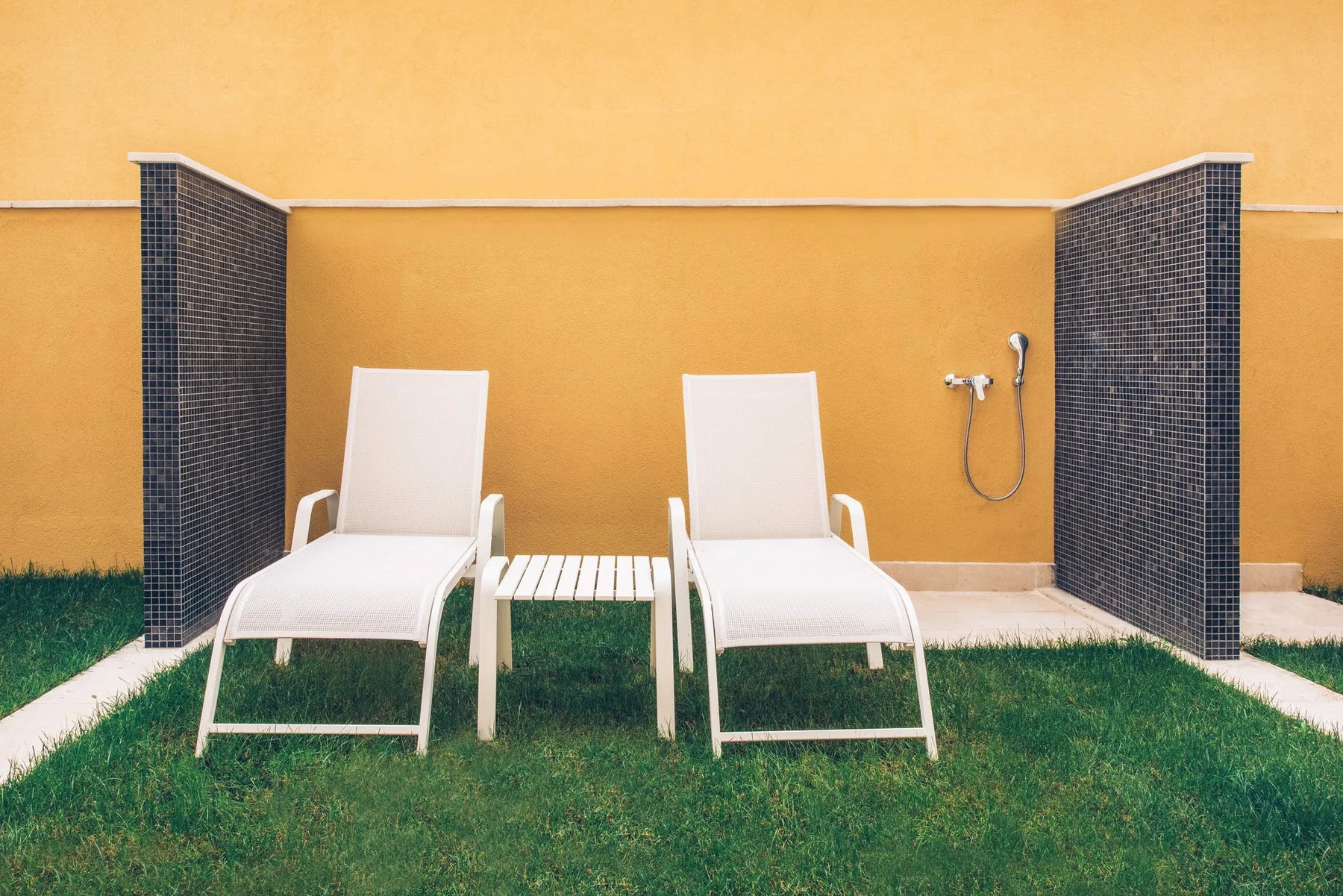 Two sun loungers and an outdoor shower in the garden