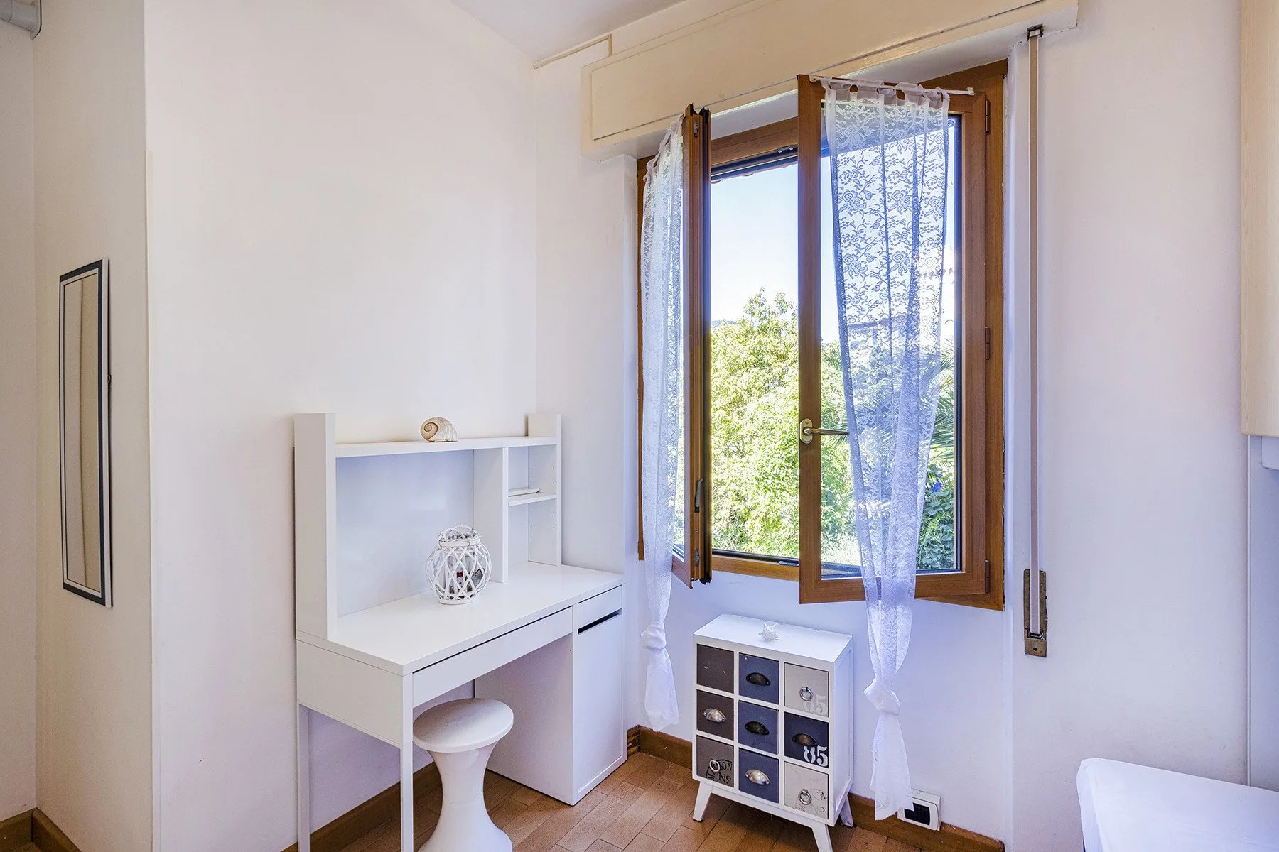 Una habitación luminosa con un escritorio junto a una ventana abierta.