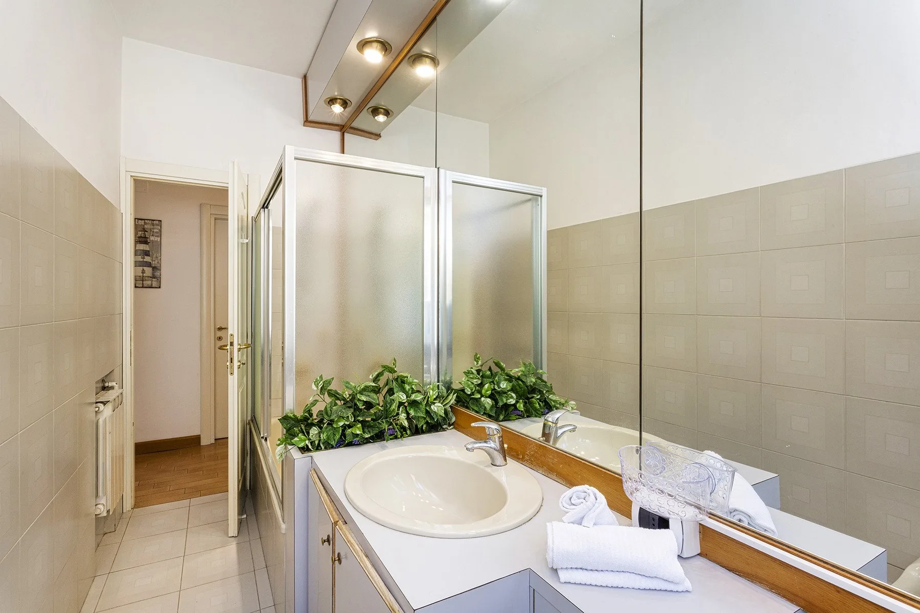 Un lavabo de baño con espejo grande y plantas frondosas.