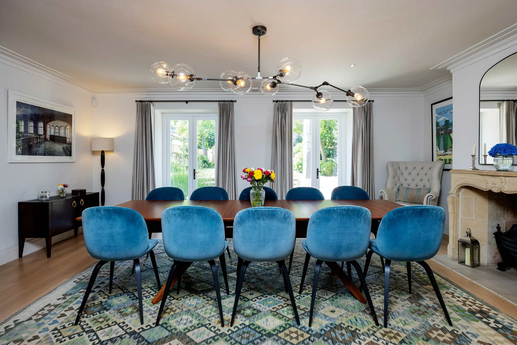 Comedor con una mesa larga, asientos azules y ventanas altas.
