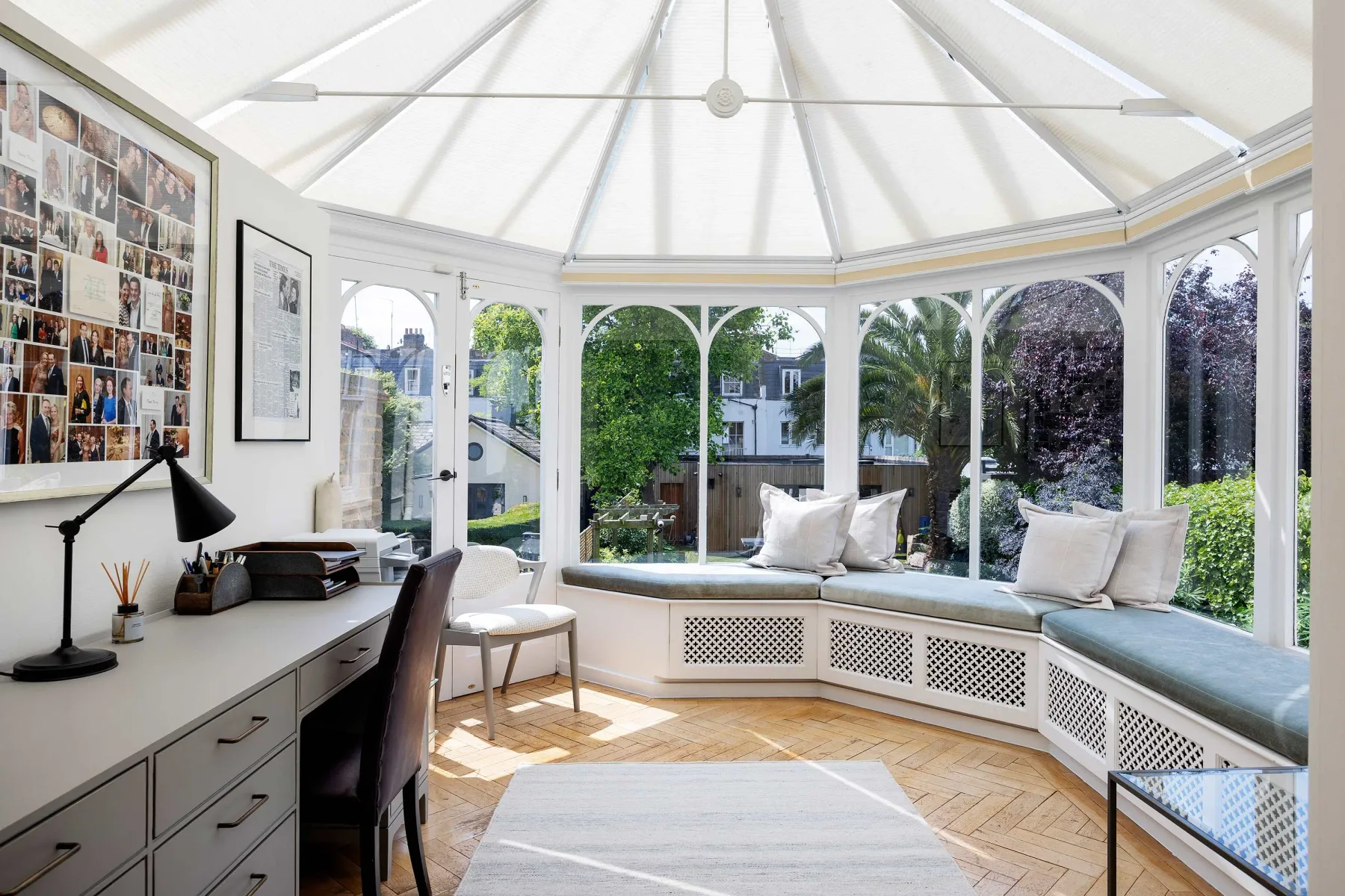 Un solárium luminoso con asientos junto a ventanas curvas y vistas al jardín.