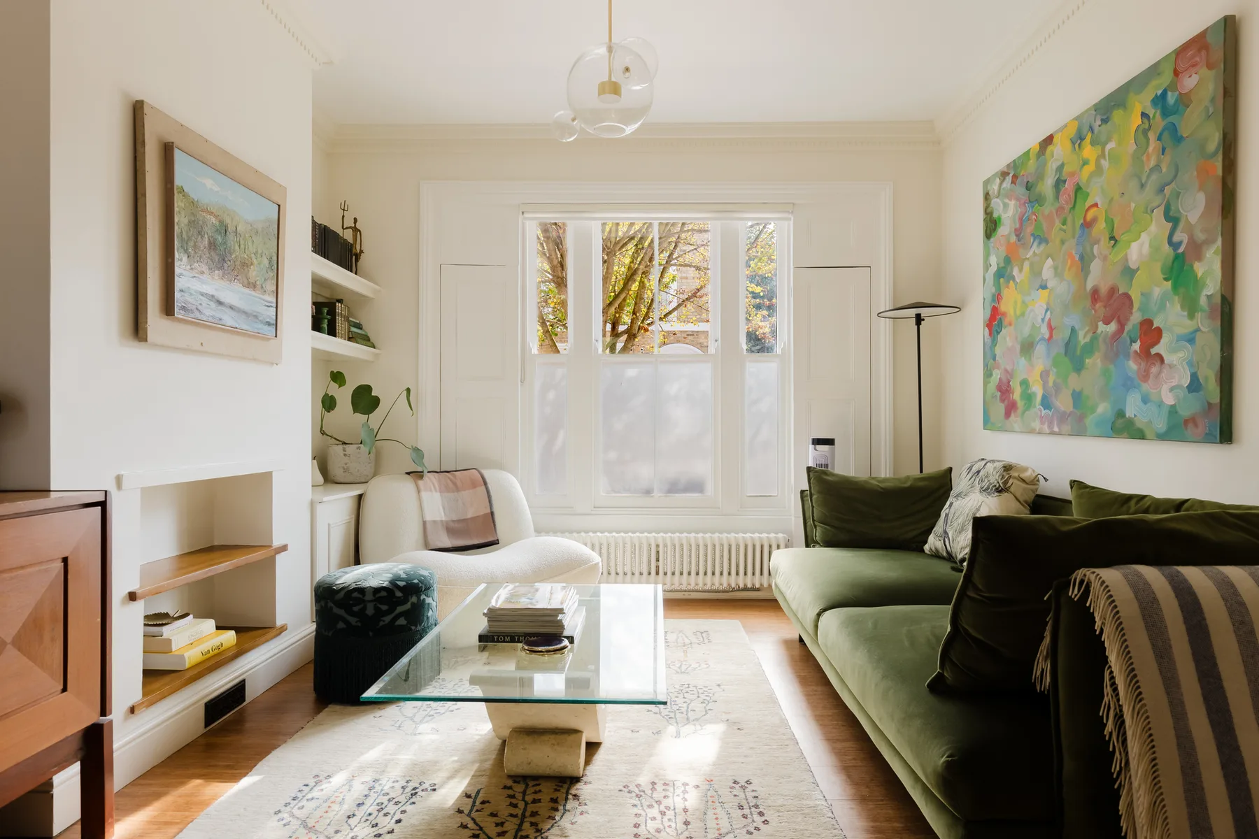 Una sala luminosa con asientos, una mesa de centro de vidrio y arte colorido en la pared.