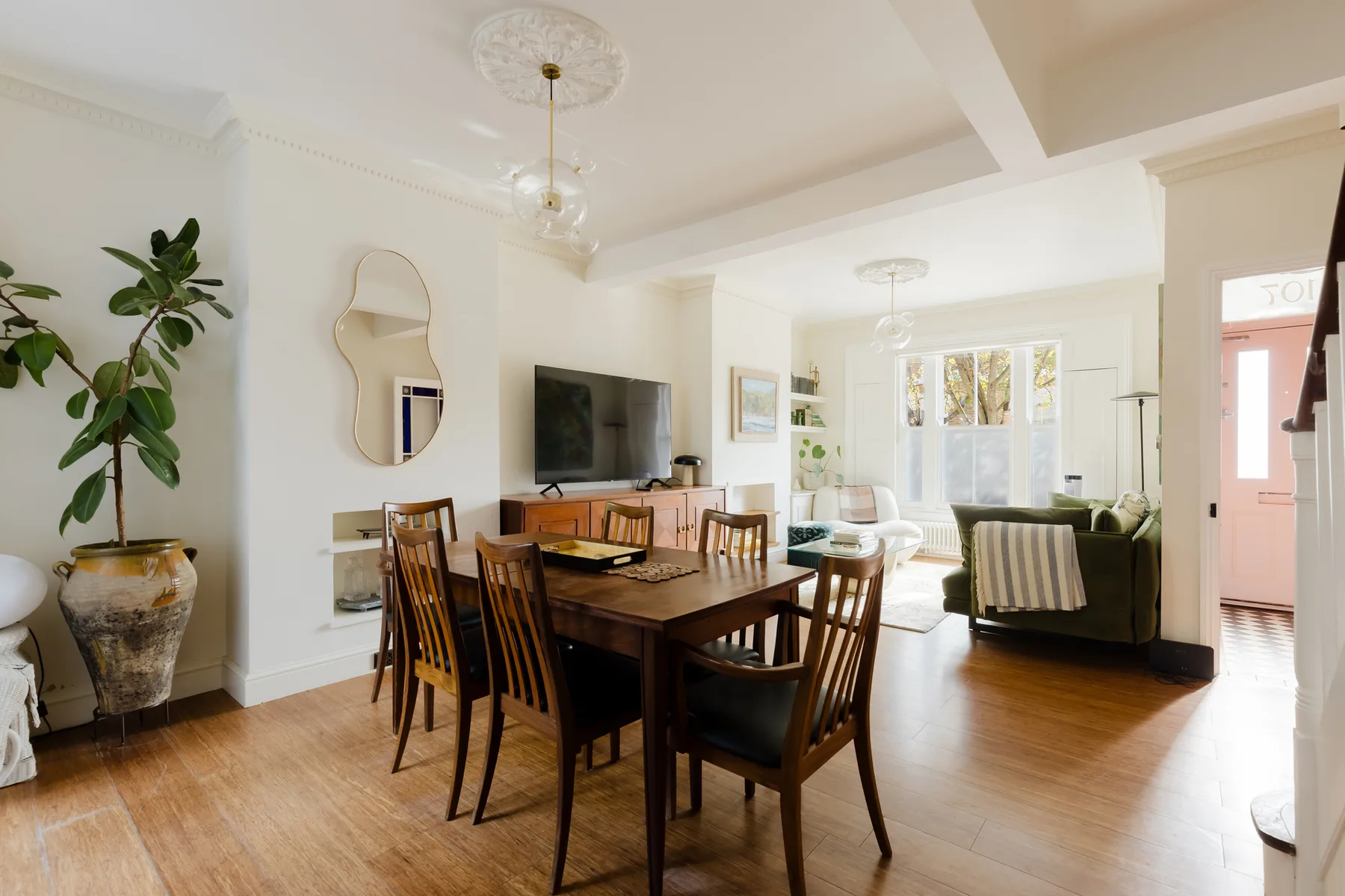 Un comedor comunica con una sala luminosa con ventanas grandes.