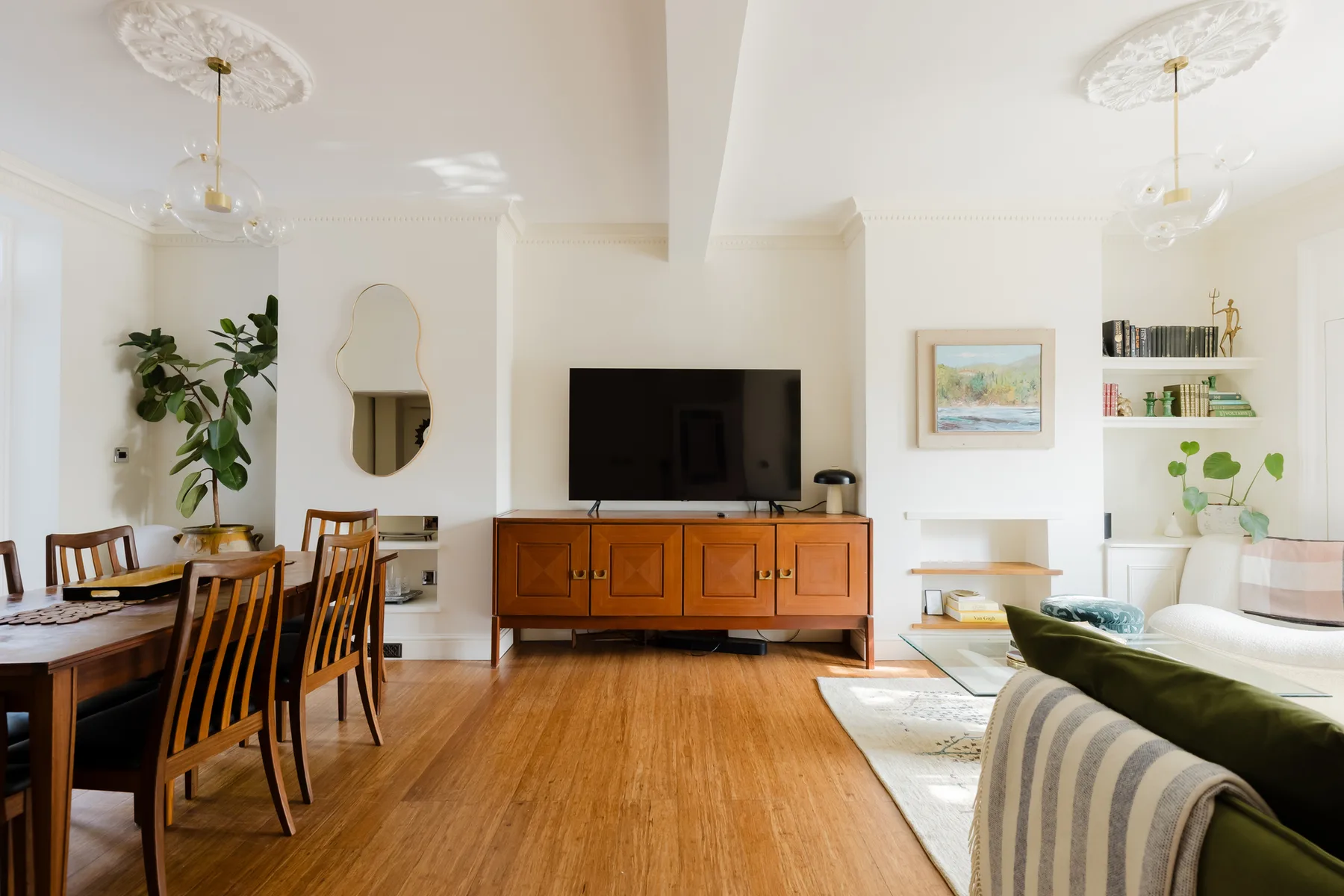 Una luminosa sala de estar y comedor con televisor y mesa de comedor de madera.
