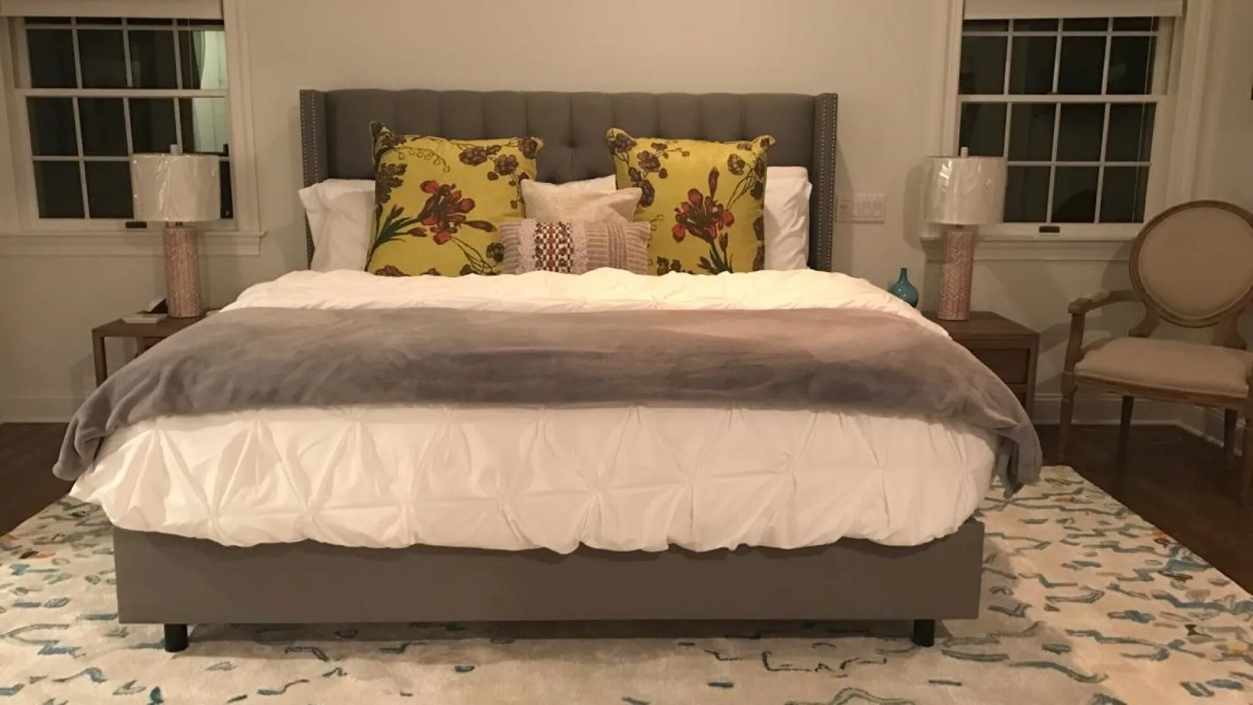 Un dormitorio con una cama bien tendida y cojines decorativos estampados.