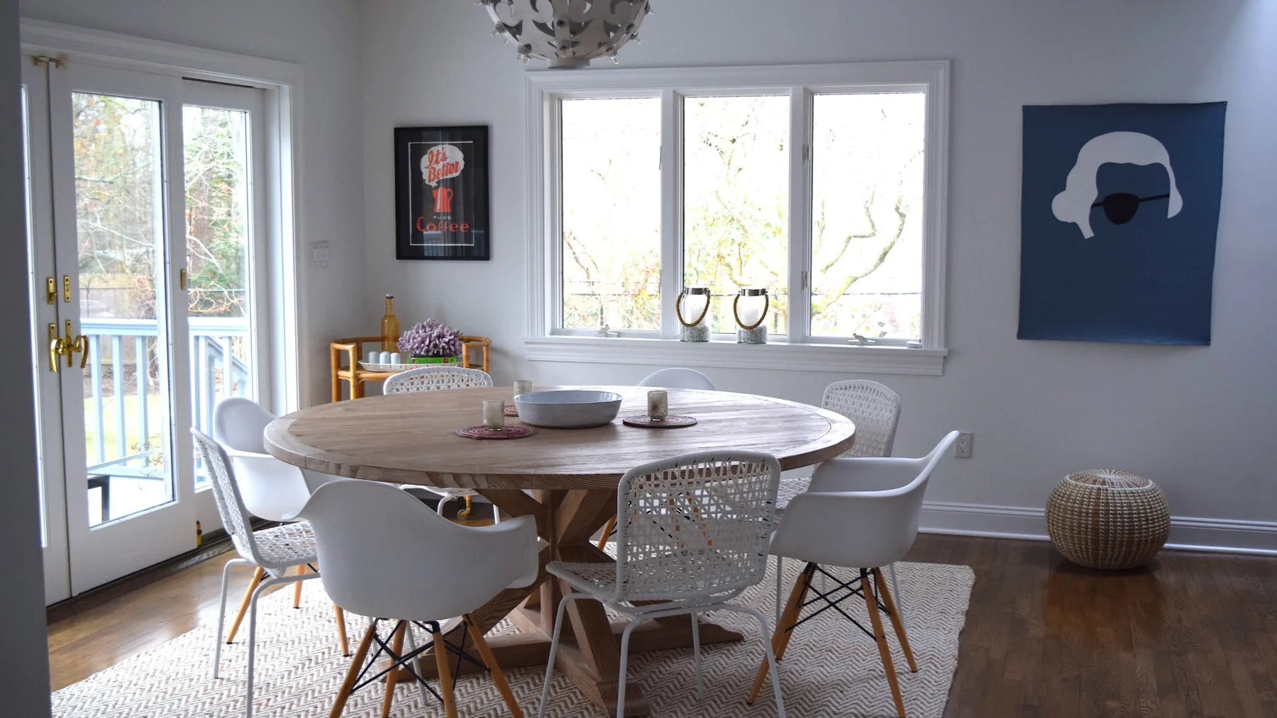 Un comedor luminoso con una mesa redonda de madera y ventanas grandes.