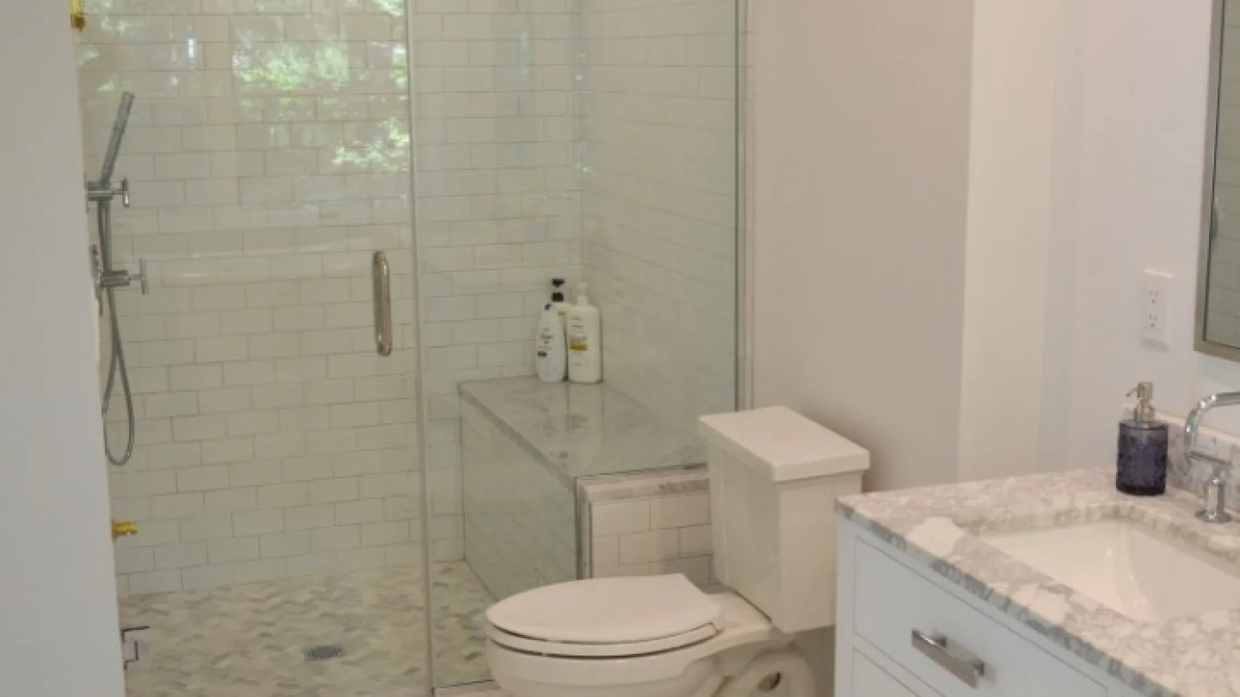 Un baño con ducha de vidrio, inodoro y lavabo con mueble.