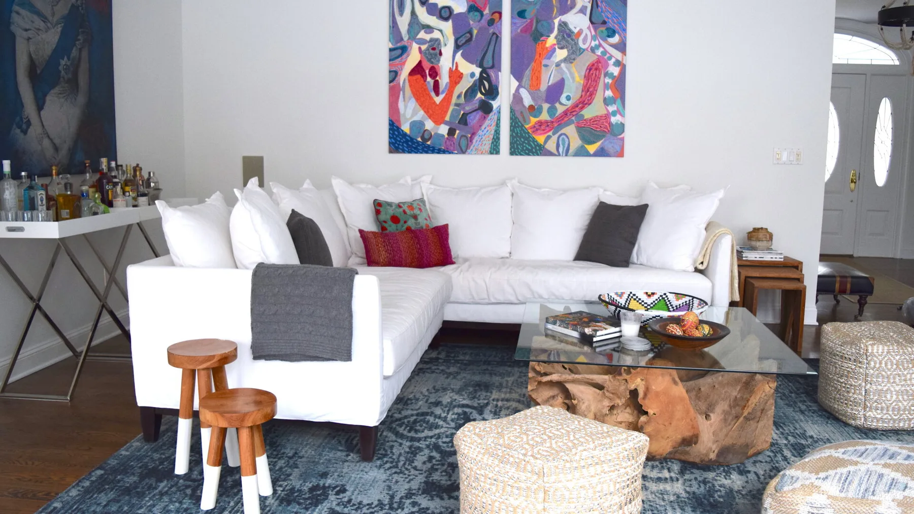 Una sala luminosa tiene asientos blancos, arte colorido en la pared y una mesa de centro de vidrio.