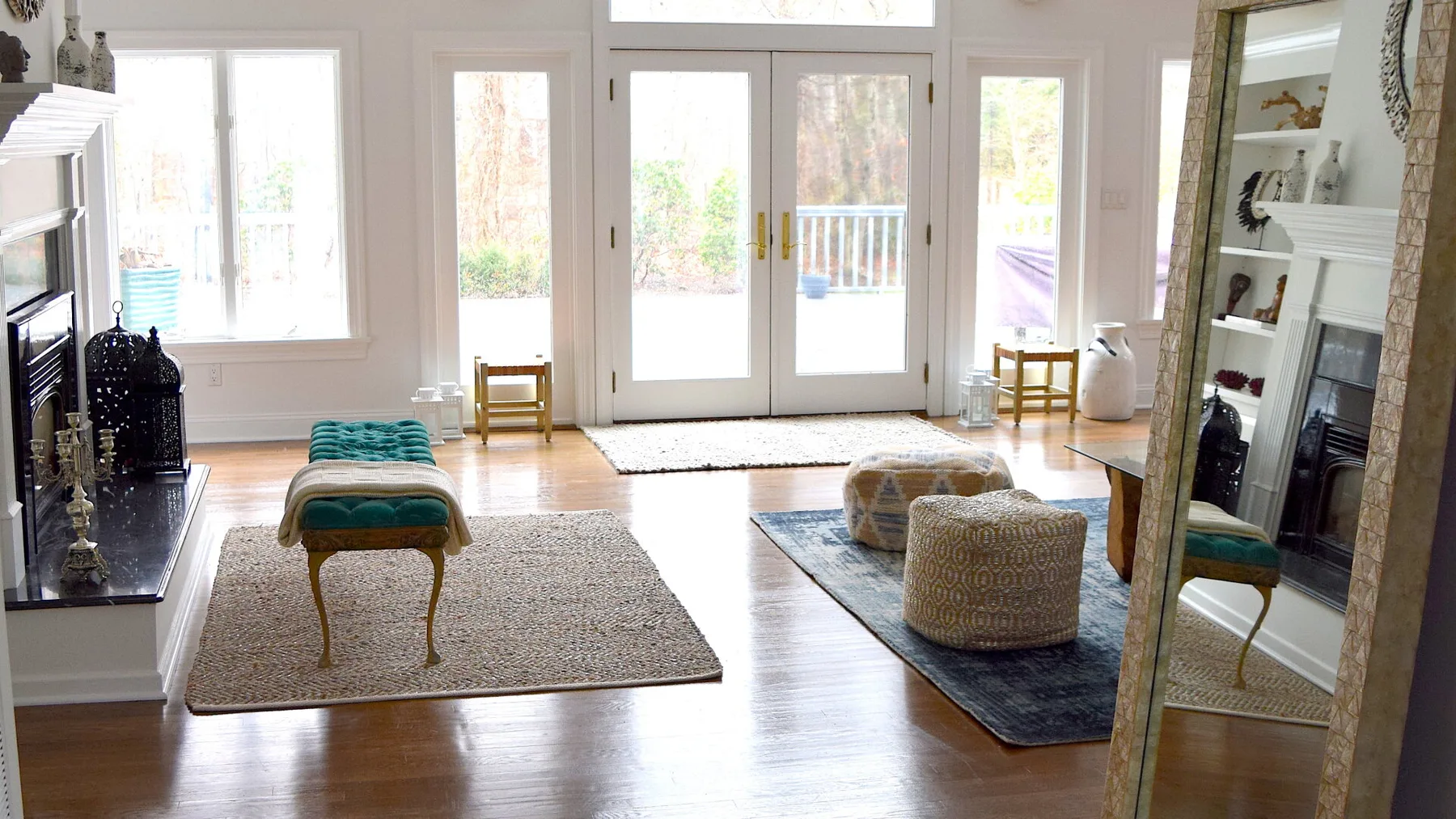 Una sala luminosa con asientos, alfombras y grandes ventanas y puertas.