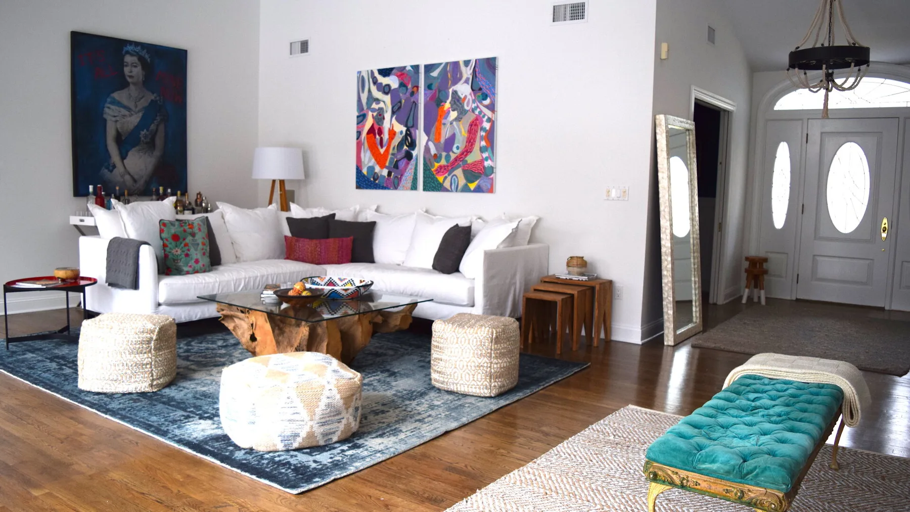 Una sala luminosa con asientos blancos, una mesa baja de madera y arte colorido en la pared.