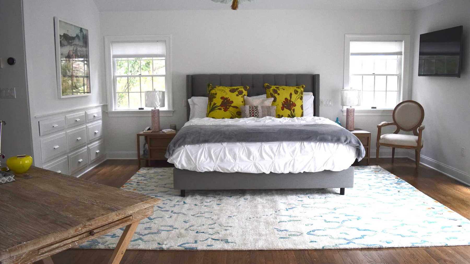 Un dormitorio con una cama, cojines coloridos y una alfombra estampada.