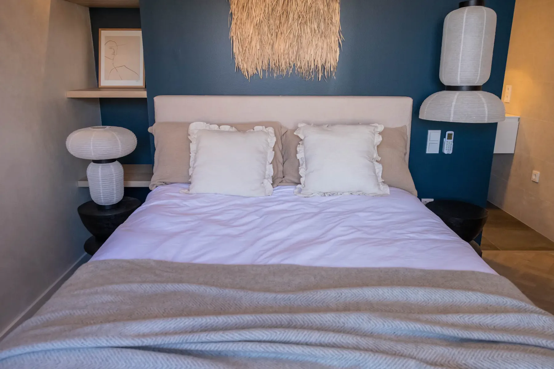 A bedroom with a bed, white pillows, and matching bedside lamps.