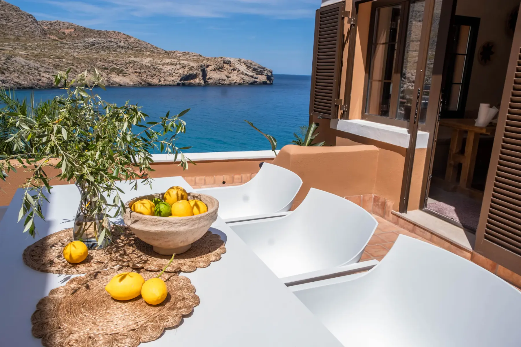 A terrace table with lemons overlooks the sea.