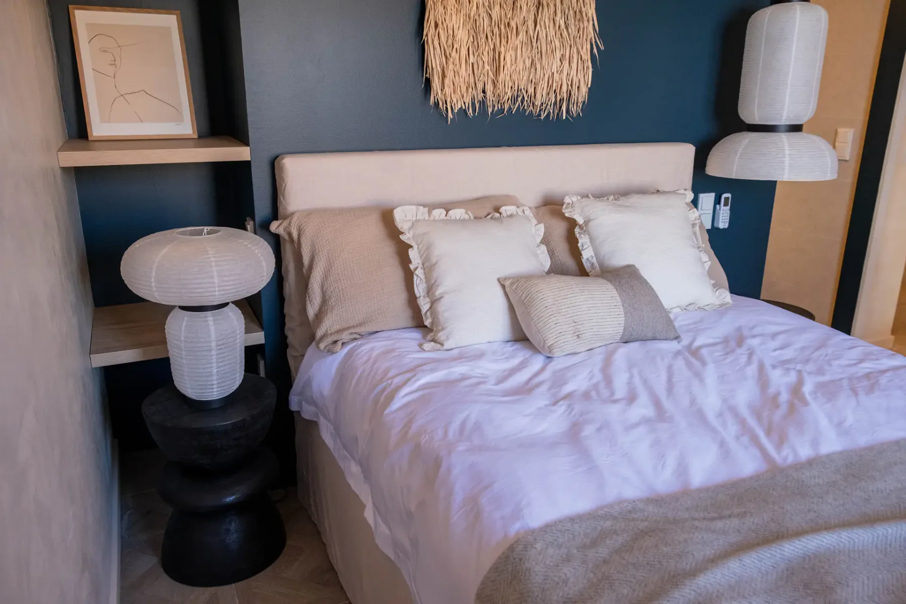 A bedroom with a bed against a dark blue accent wall.