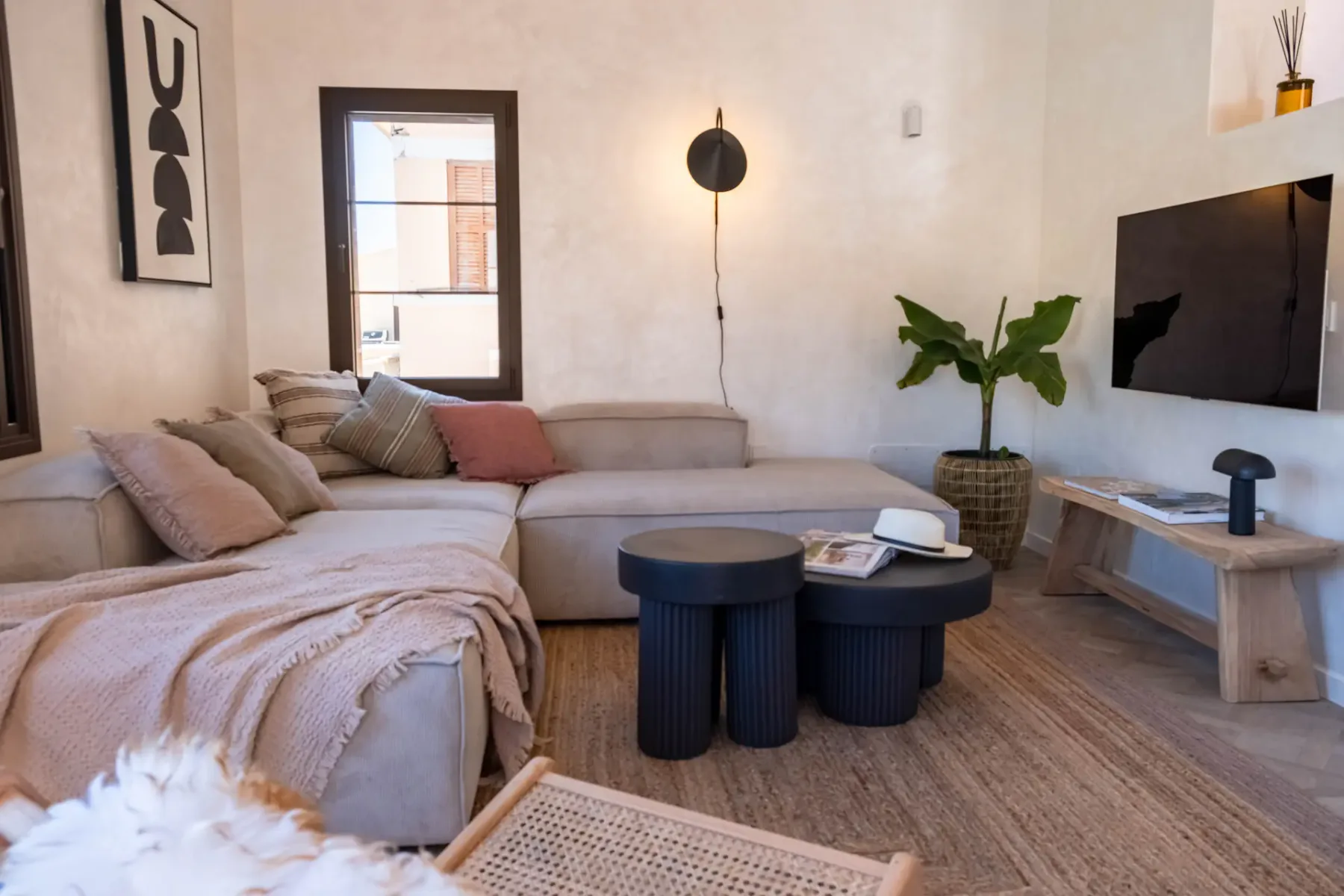 A living room with sectional seating, a coffee table, and a wall-mounted television.