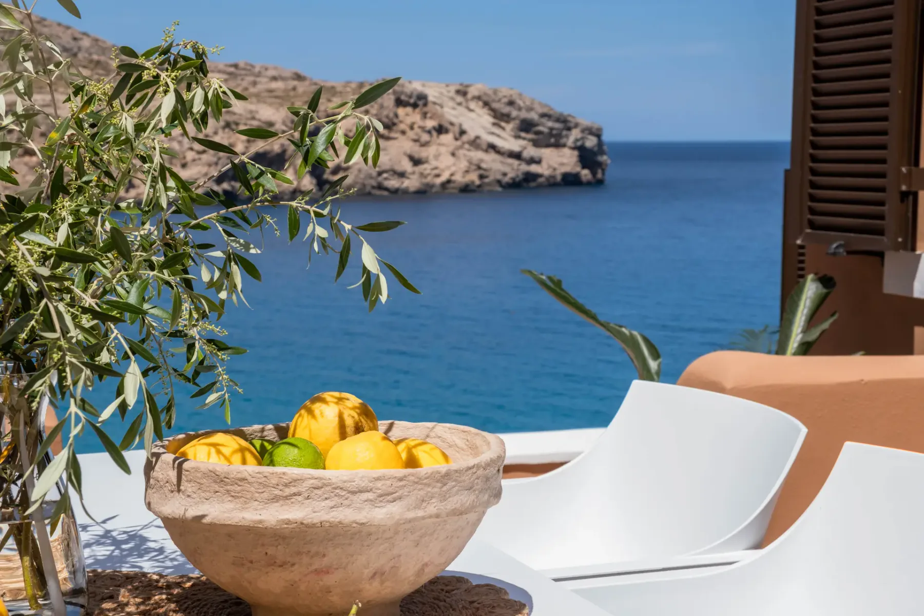 A seaside terrace overlooks blue water and a rocky coastline.